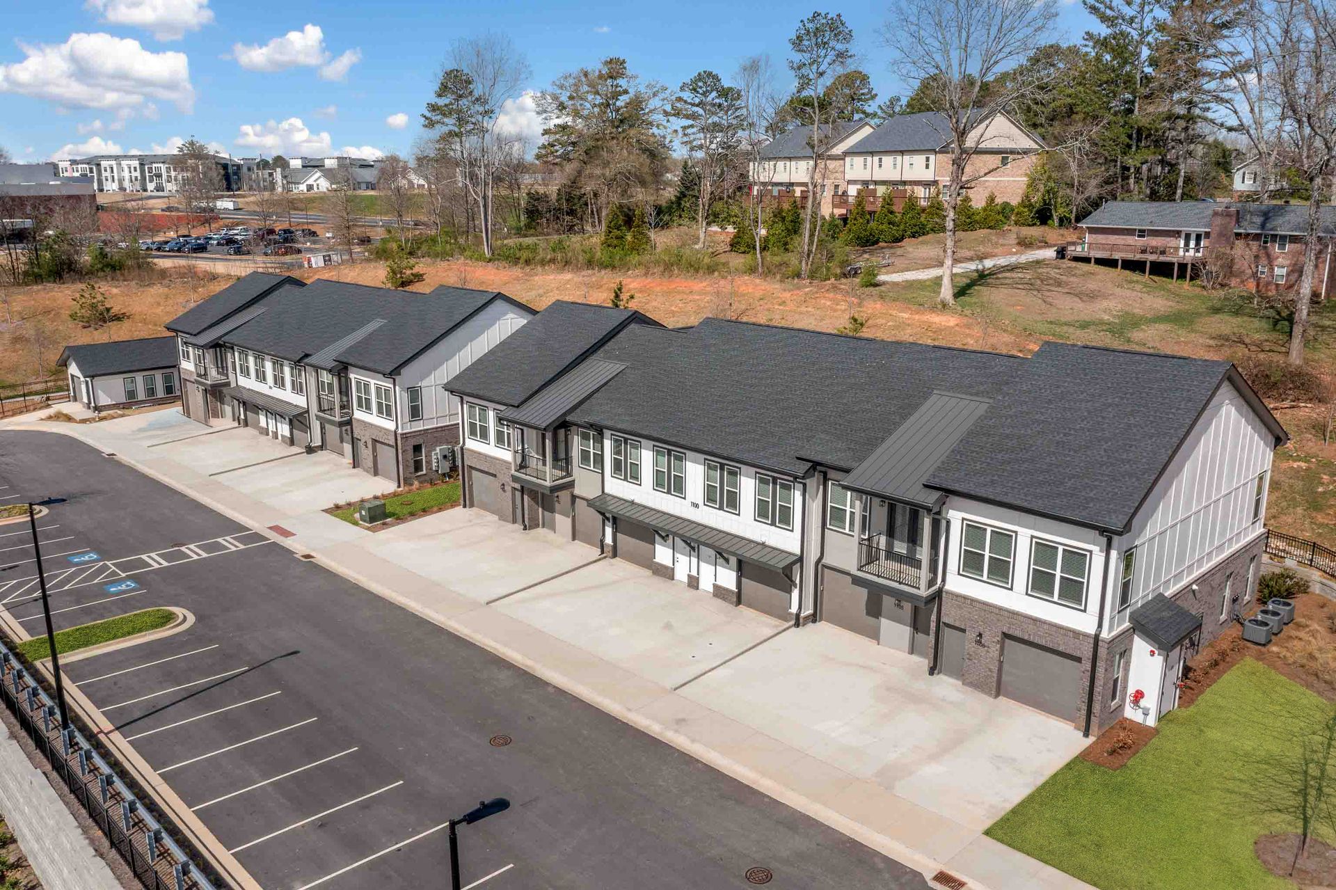 Row of townhouses with gray and white exteriors, asphalt parking lot.