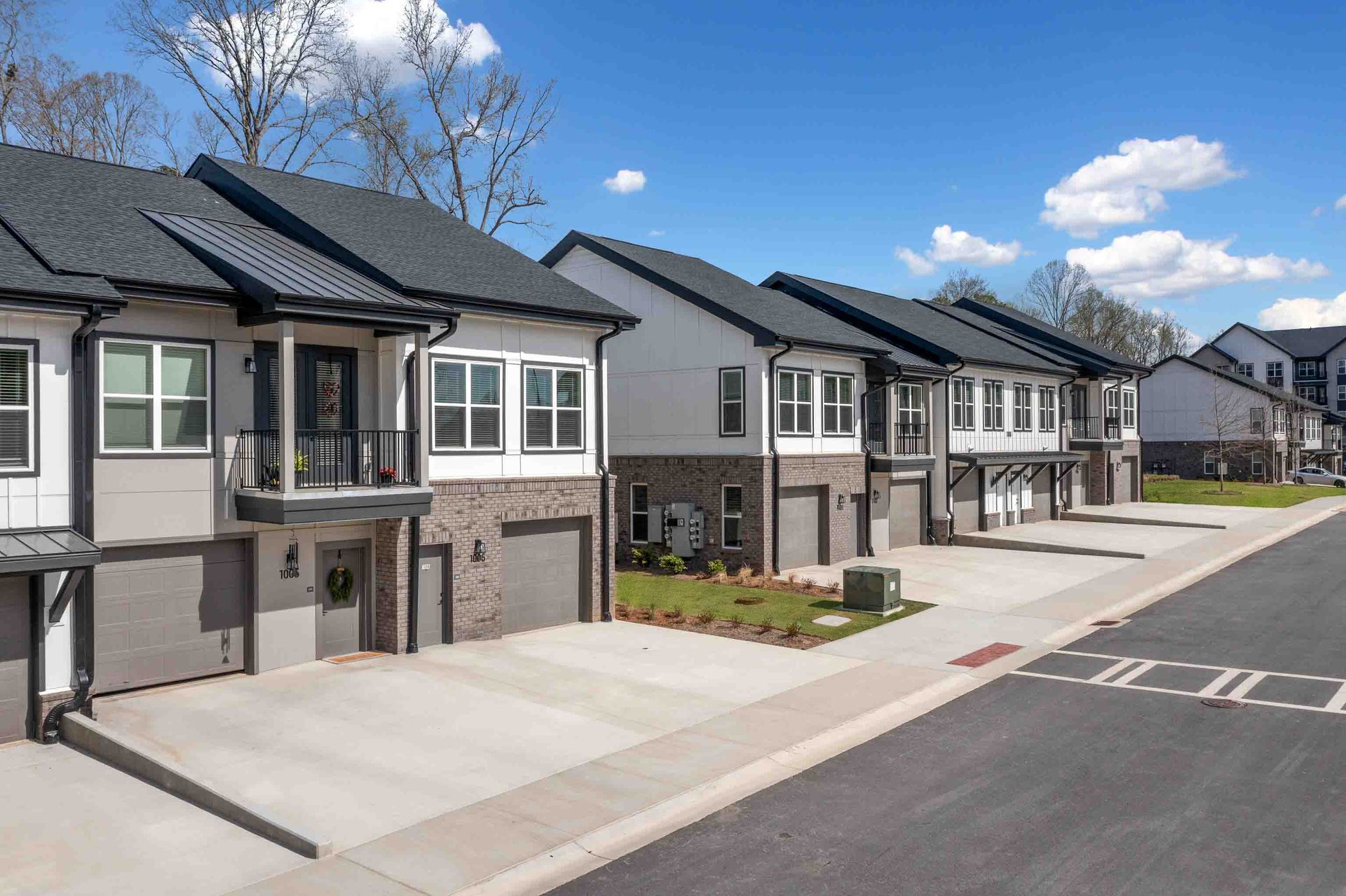 Row of modern townhouses with grey garage doors and dark gray roofs.