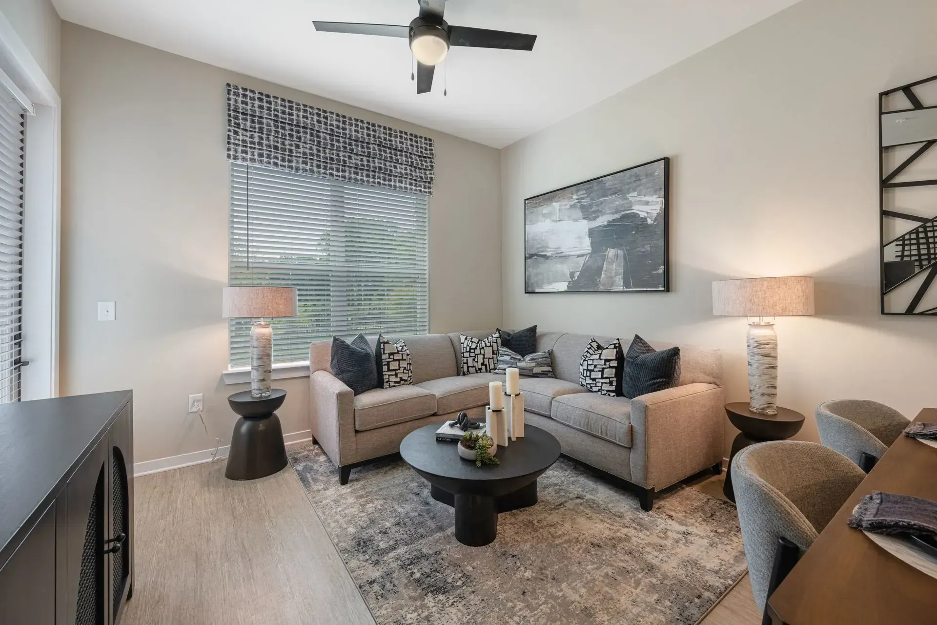 A living room with a large sectional couch and a ceiling fan