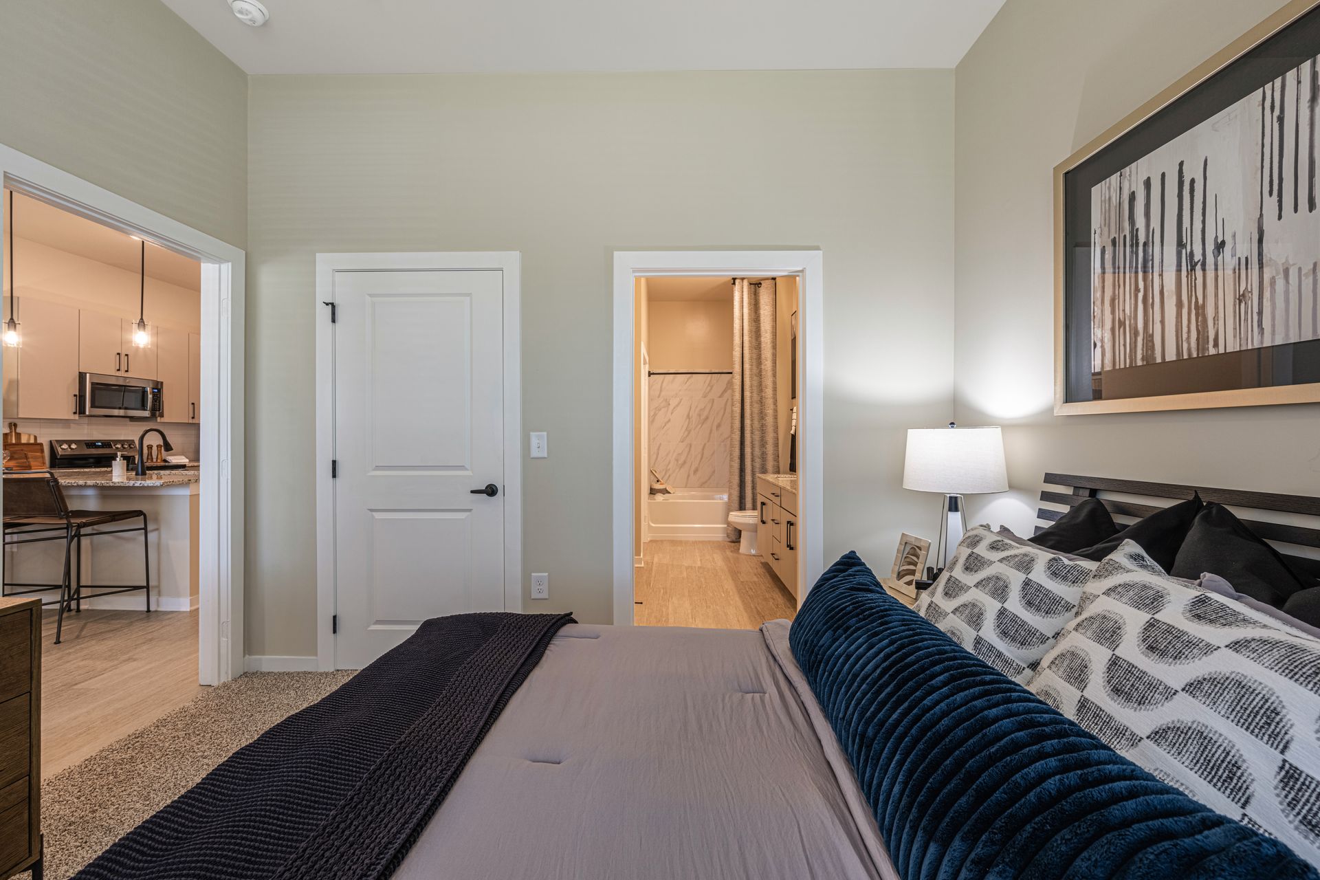 Bedroom with bed, doorway to kitchen, doorway to bathroom, artwork.