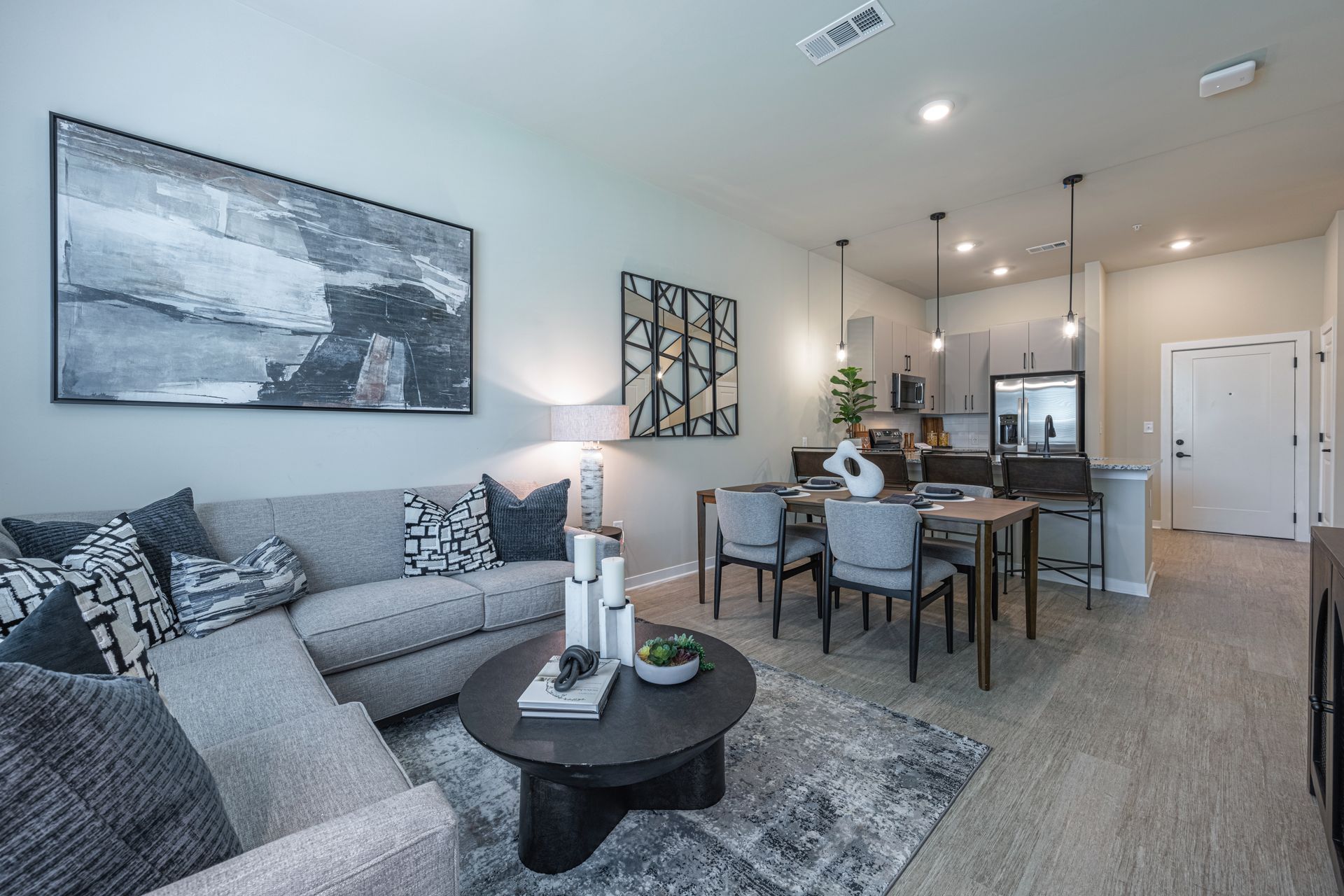Living room with sectional sofa, dining area, and open kitchen in a modern apartment.