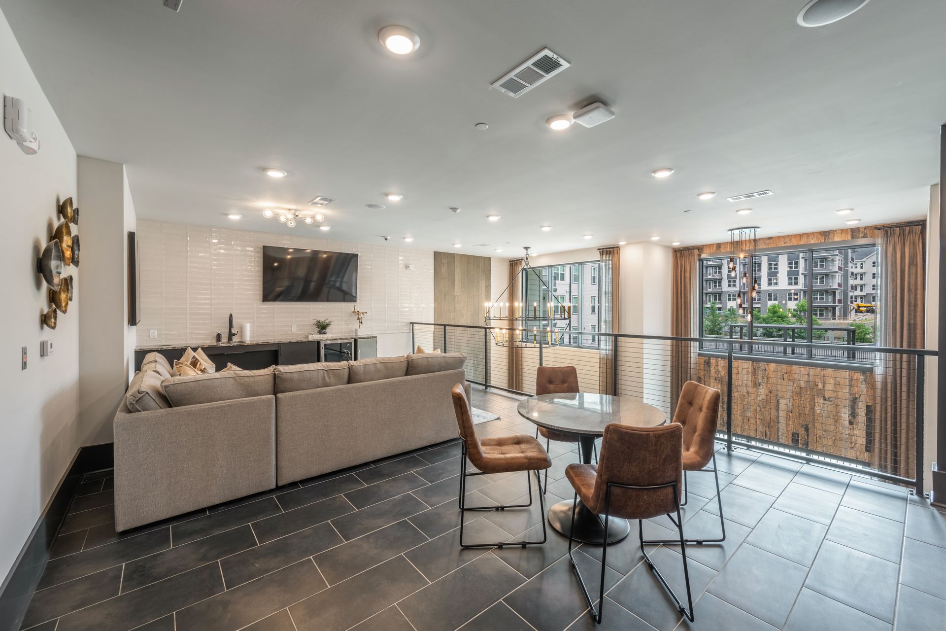 Modern lounge area with gray sectional sofa, round table, and balcony view.
