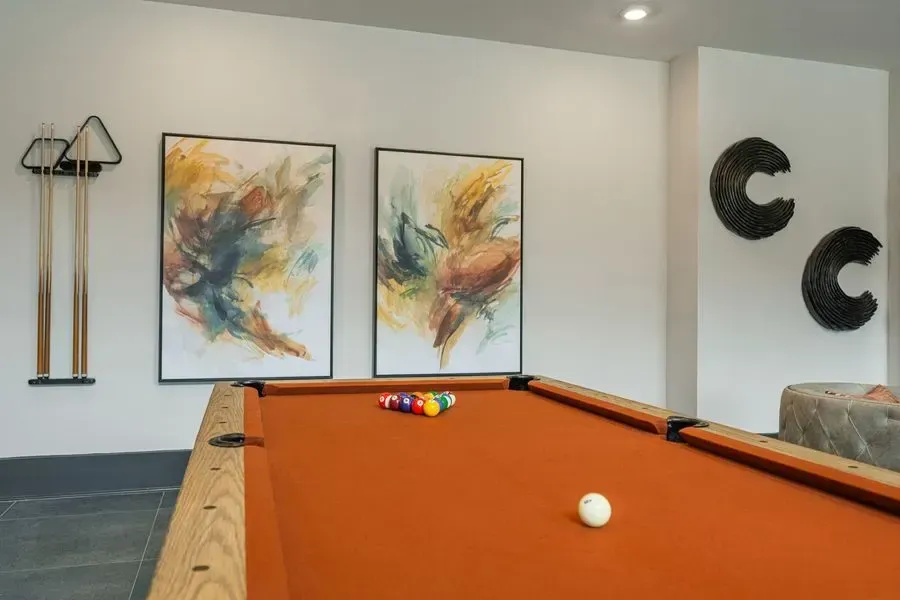 A pool table in a room with paintings on the wall