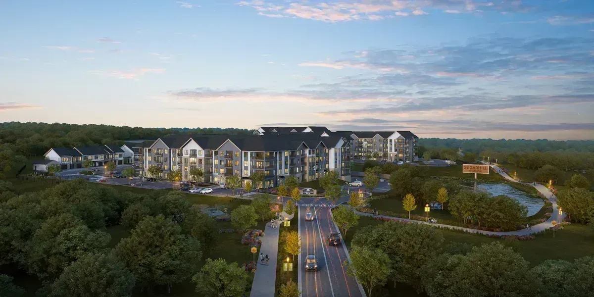 An aerial view of a large apartment complex surrounded by trees and a road.