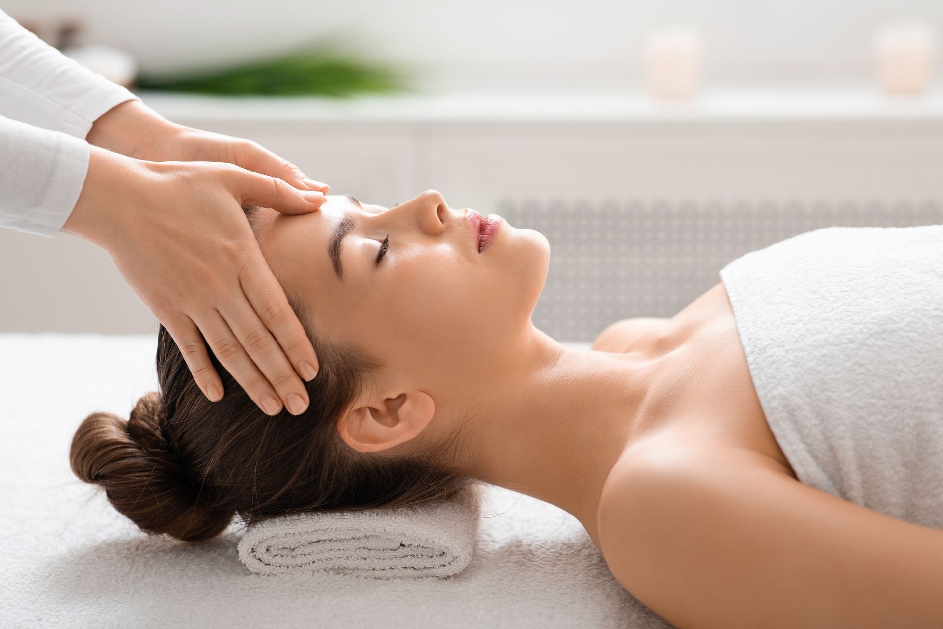 A person's leg is being waxed at a spa, the technician wears blue gloves, pink wax.