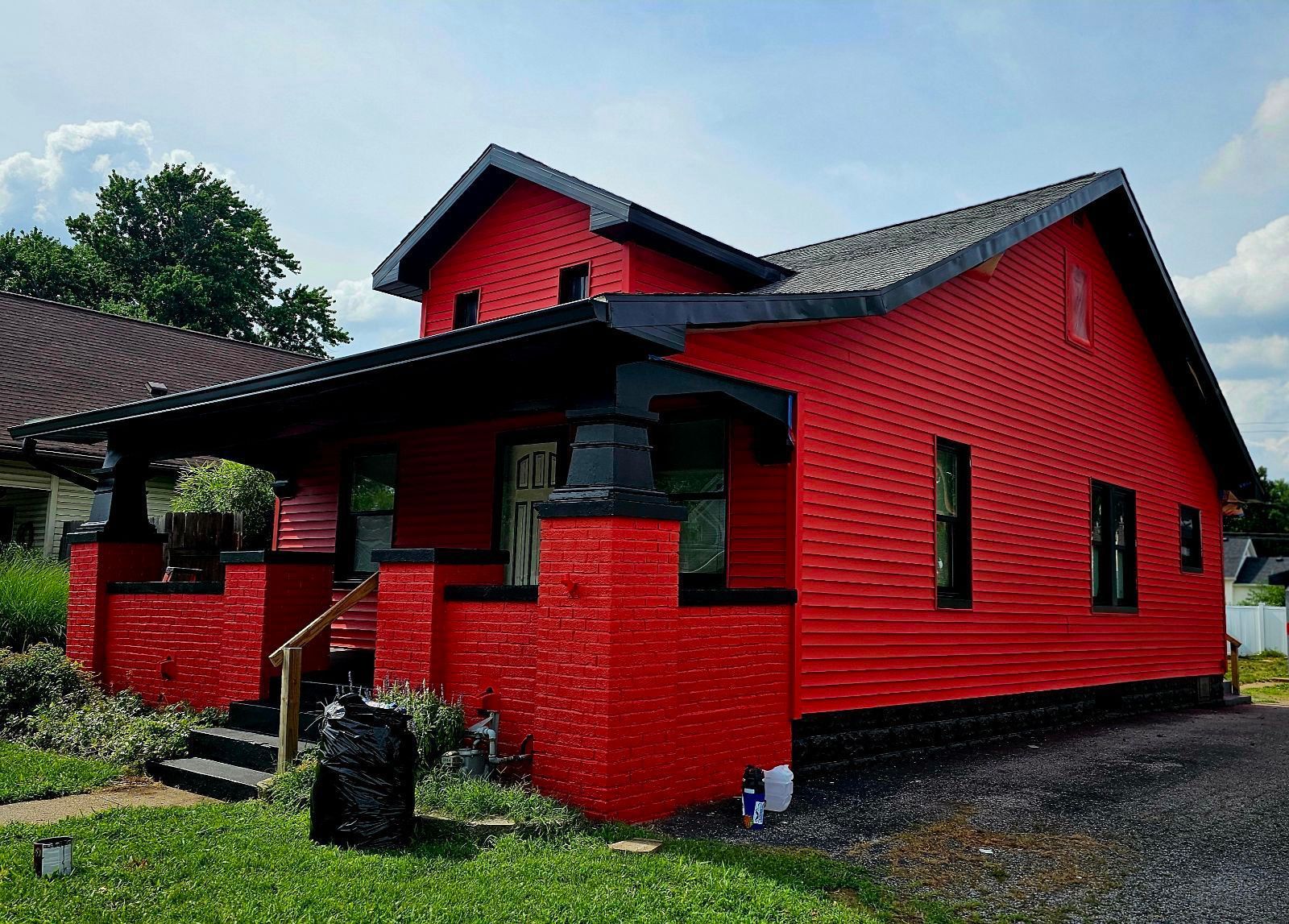 Red house with black trim and porch on a sunny day.