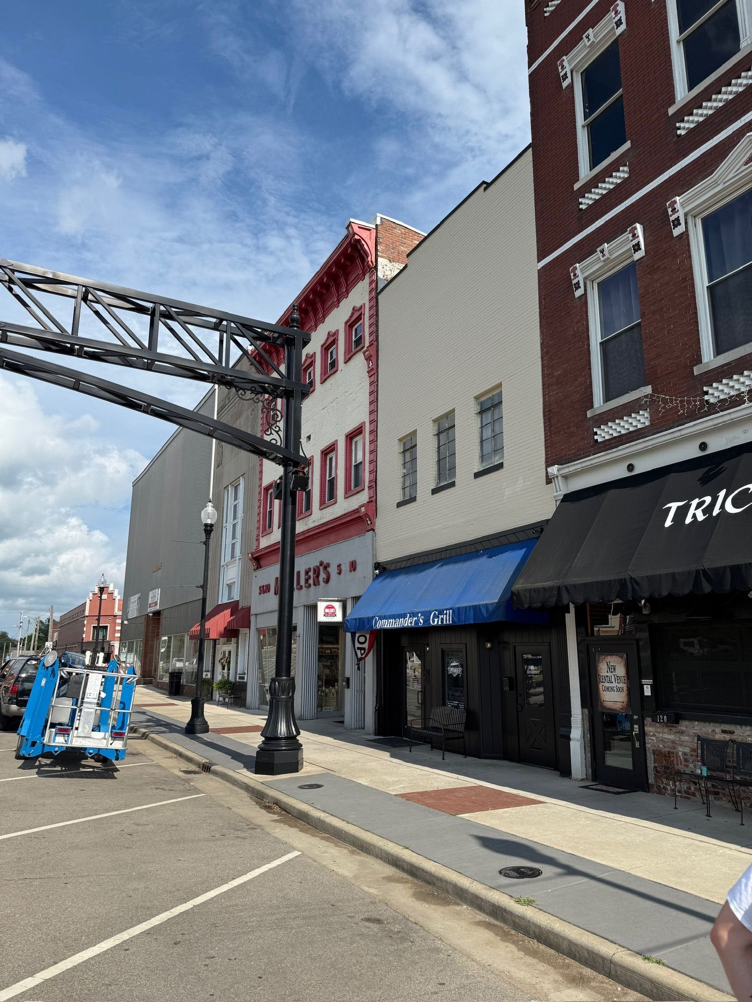 Buildings on a street, some with awnings. Blue lift in the foreground.