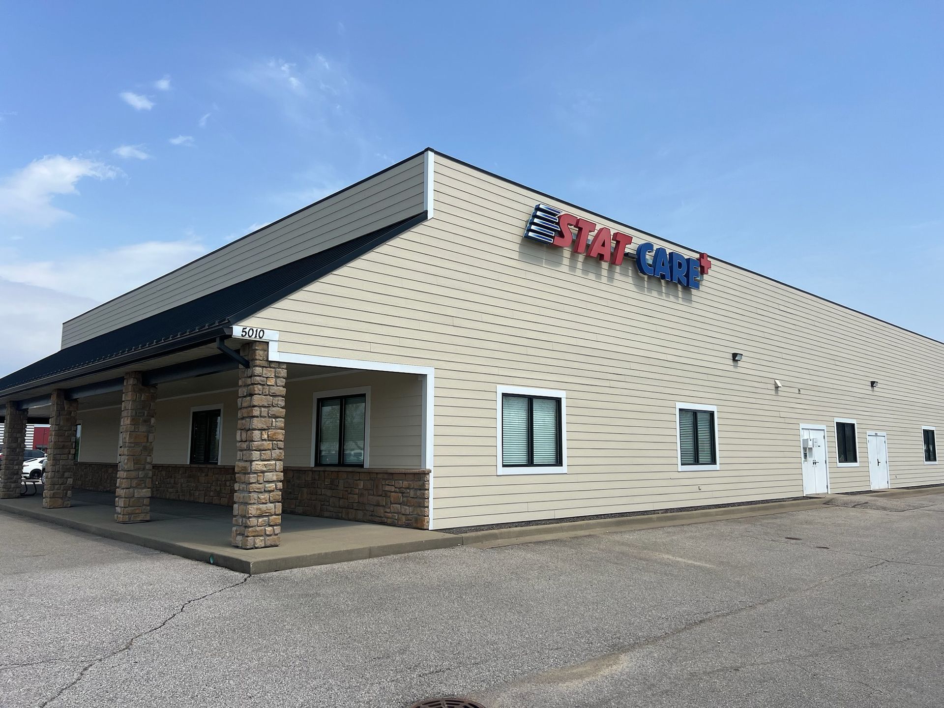Exterior of Stat-Cam building with a tan facade, stone pillars, blue and red logo on a sunny day.