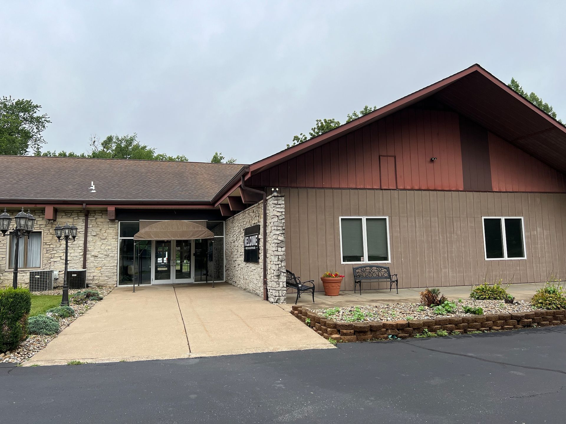 Exterior of a brick and wood building with a sloped roof, windows, and a small garden.