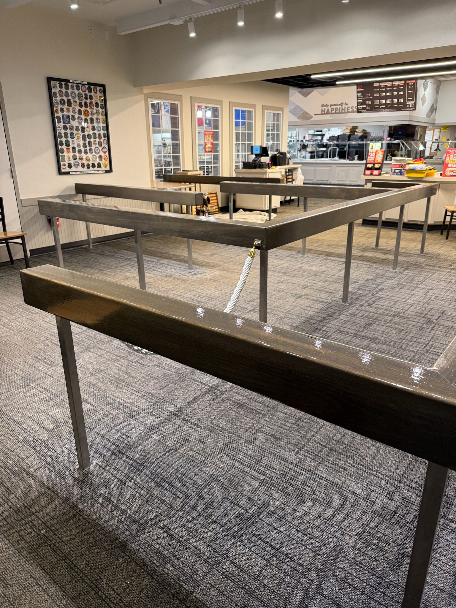 Restaurant with tables, counter, and a food service area in the background. The floor is carpeted.