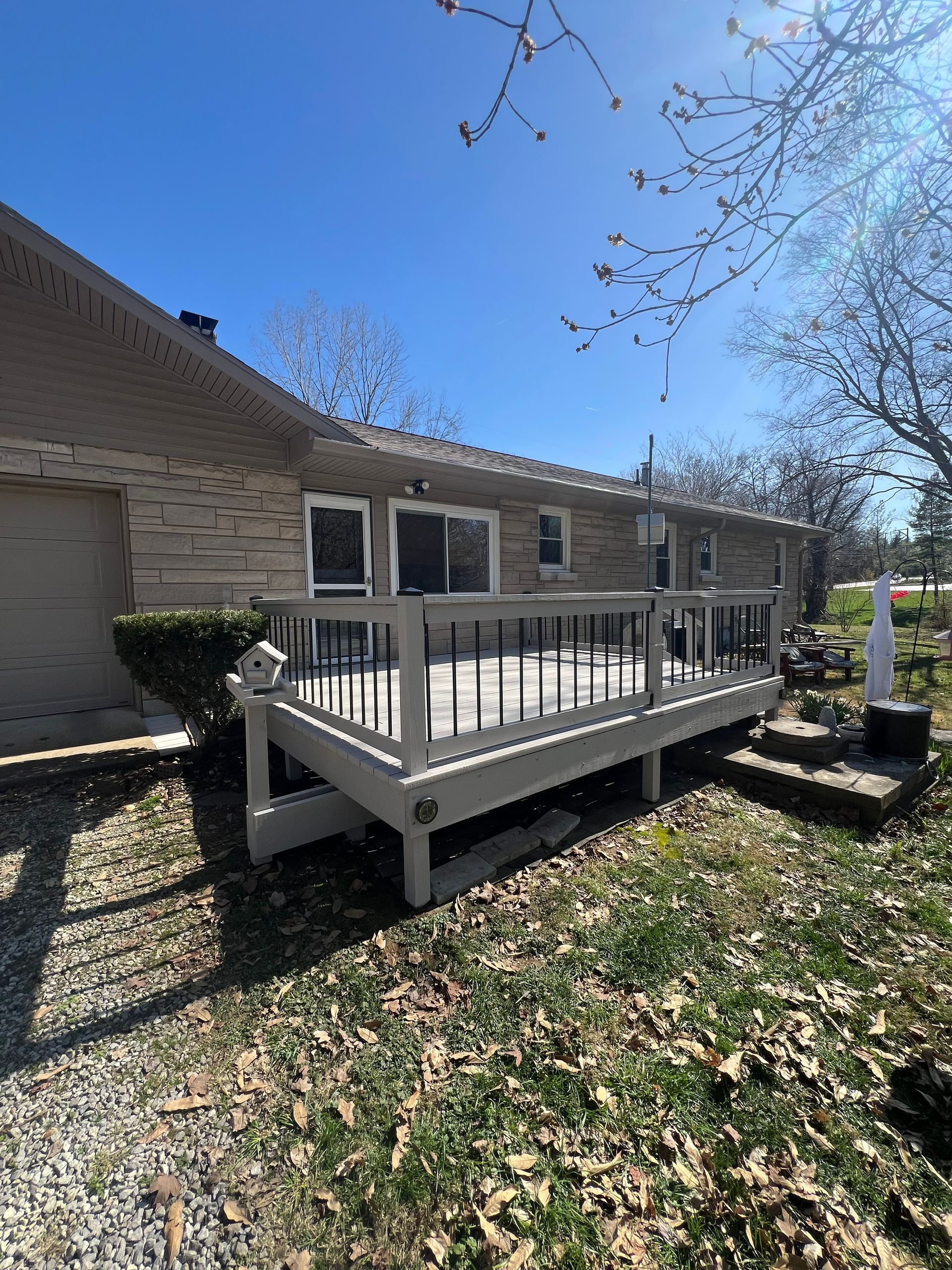 Wooden deck next to a light-colored brick house on a sunny day.