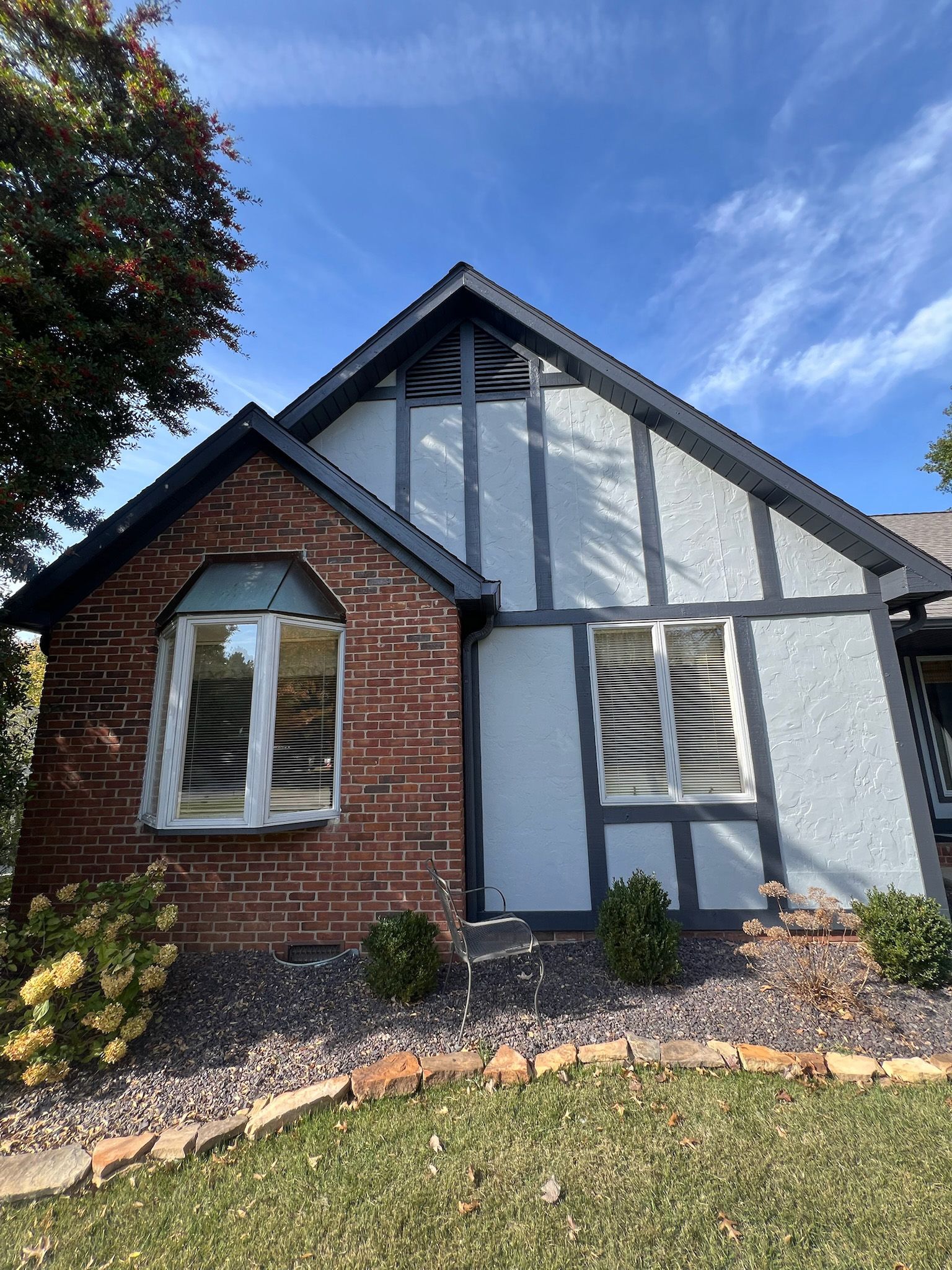 Tudor-style house with brick and stucco exterior, dark trim, and a blue sky.