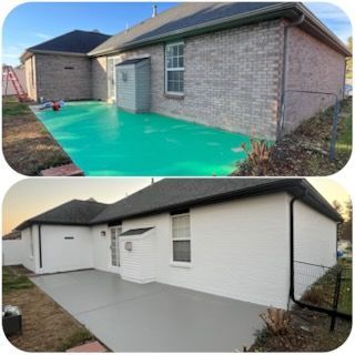 Gray-painted brick house with white trim, windows, and porch. A flowerbed with plants sits in front of the house.