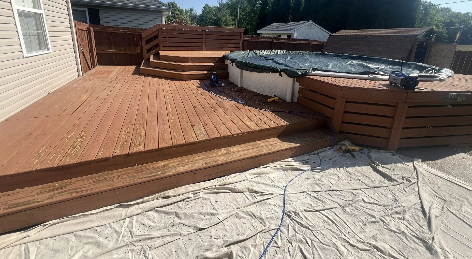 Wooden deck with integrated above-ground pool, brown stained wood, sunny day.