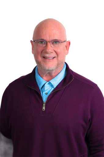 Man with glasses, bald head, and purple sweater smiling in front of white background.