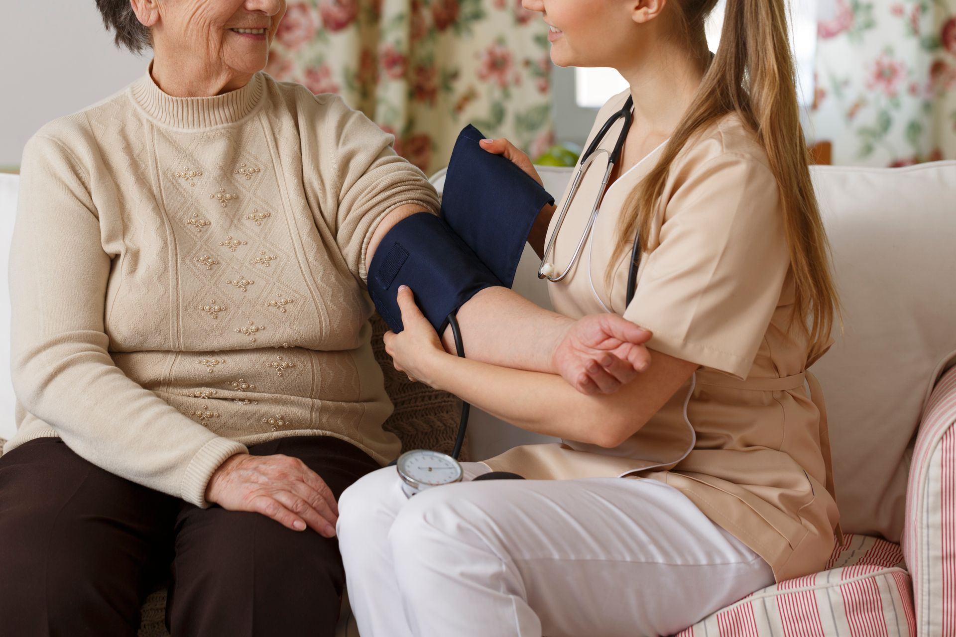 A healthcare worker takes a patient's blood pressure indoors.