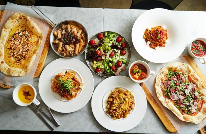 Various dishes arranged on a table: salads, pasta, bread, and stew, creating a colorful and appetizing spread.