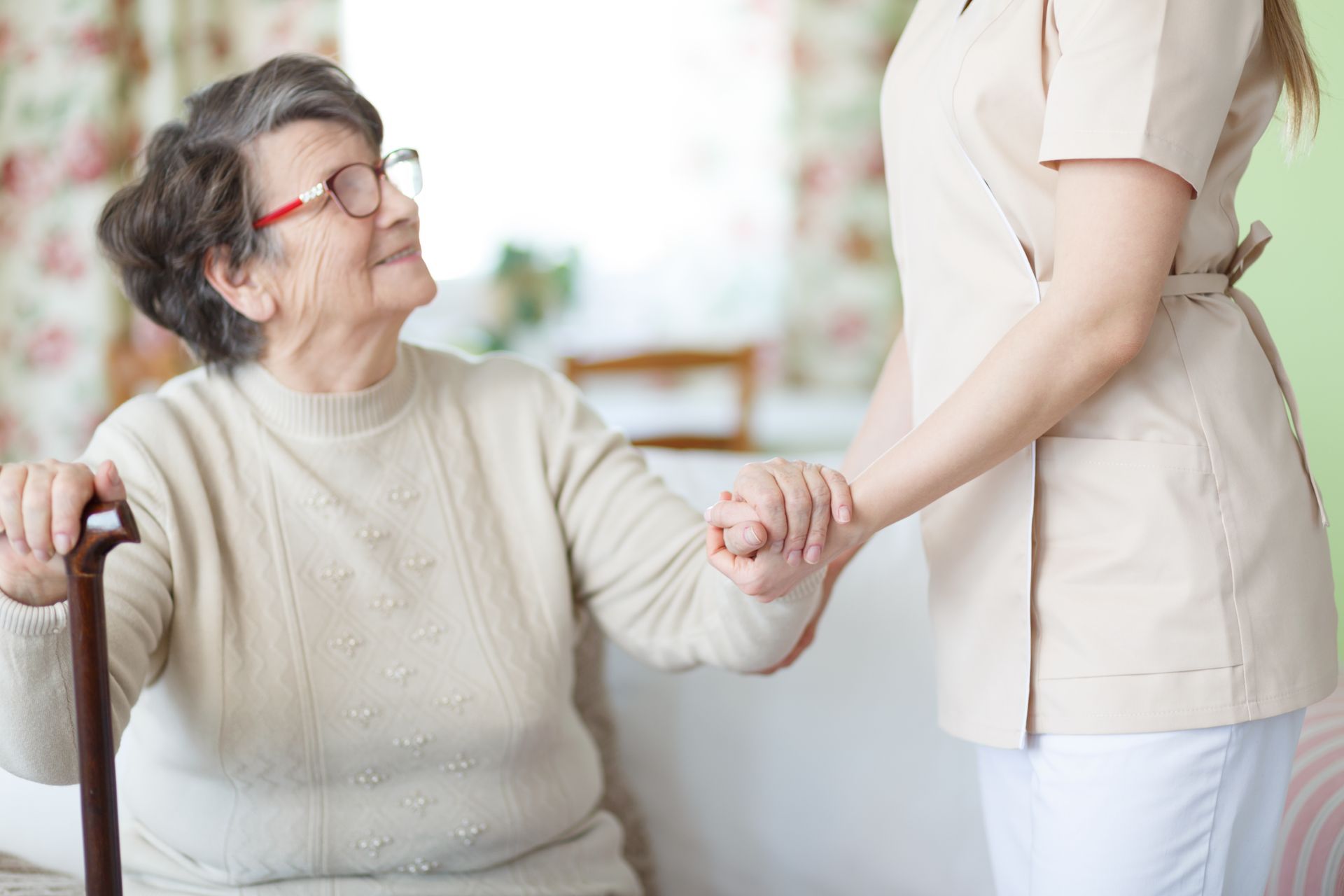 Woman with cane being assisted by another person indoors.
