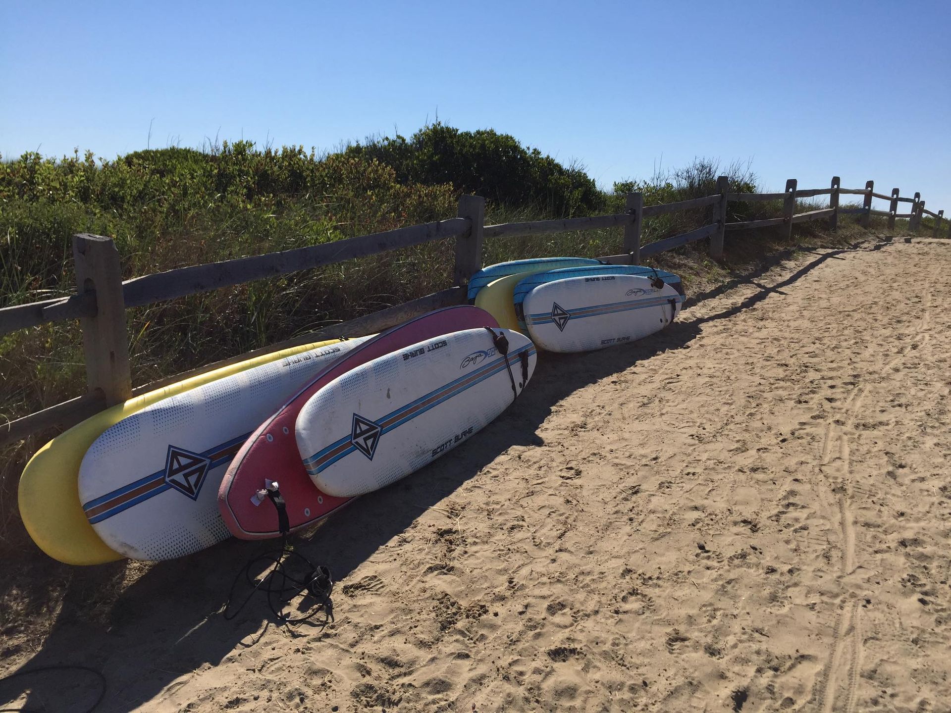 A man and a woman are standing next to each other in a park holding surfboards.