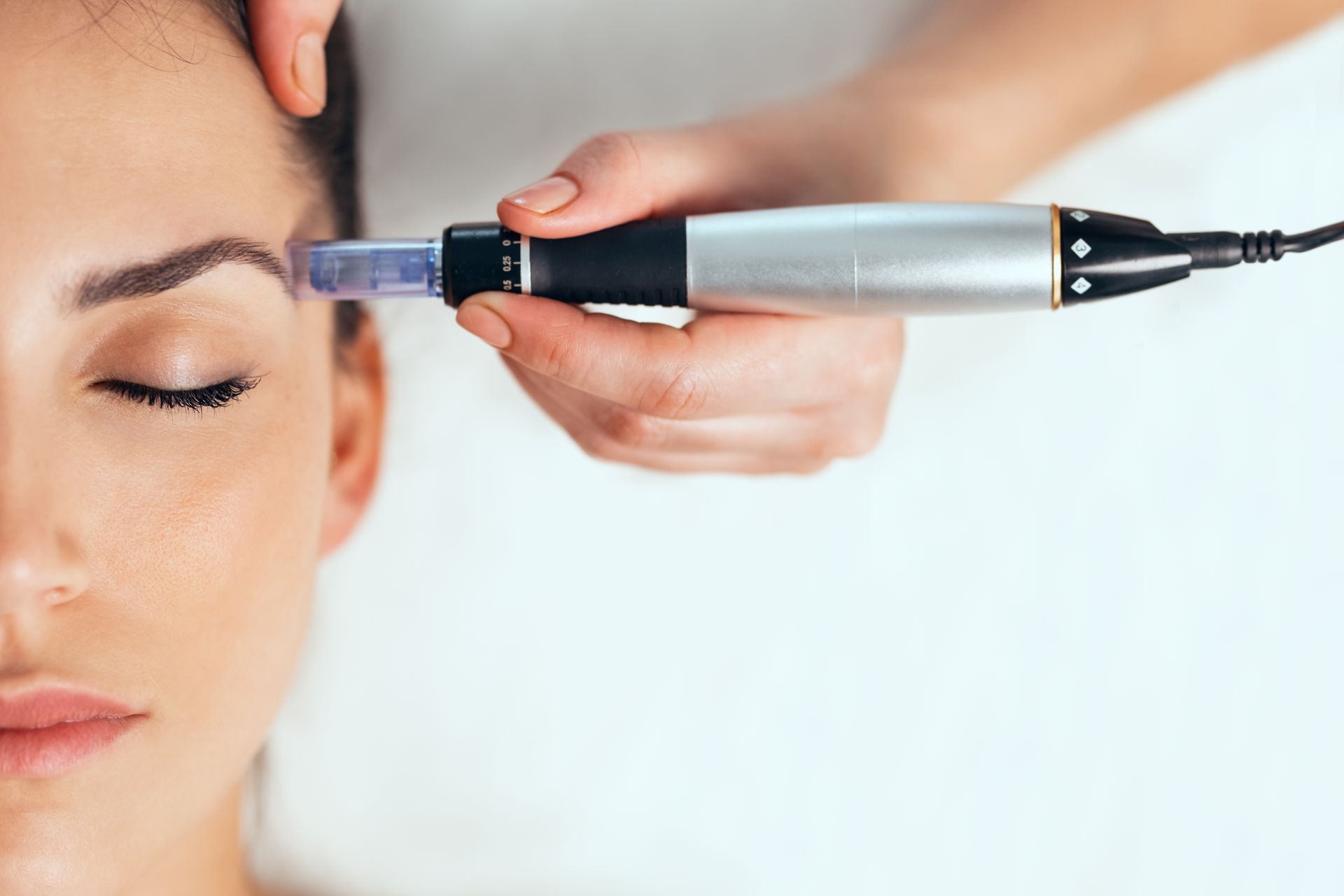 A woman is getting a microneedle treatment on her forehead.