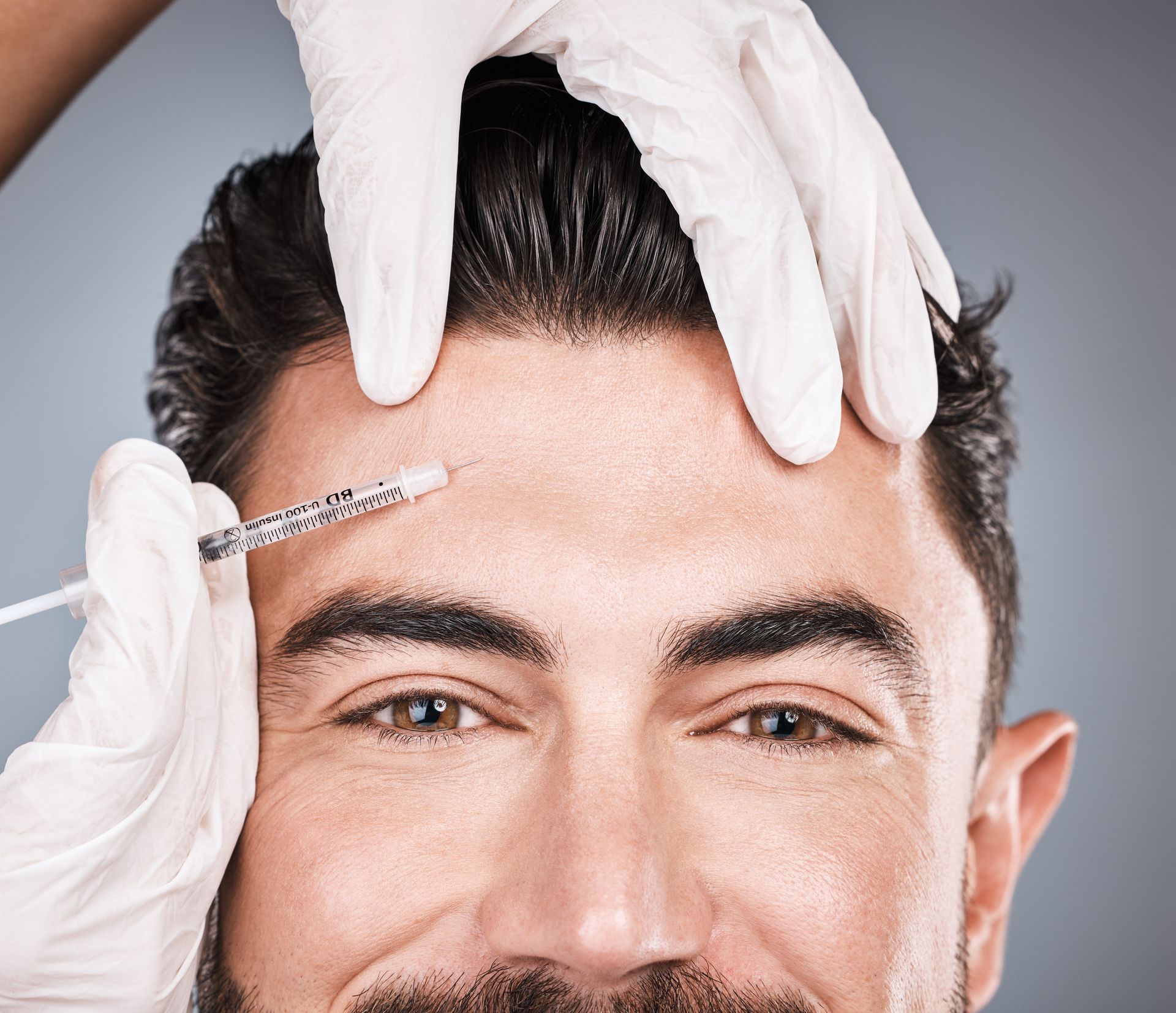 A man is getting a neurotoxin injection on his forehead.