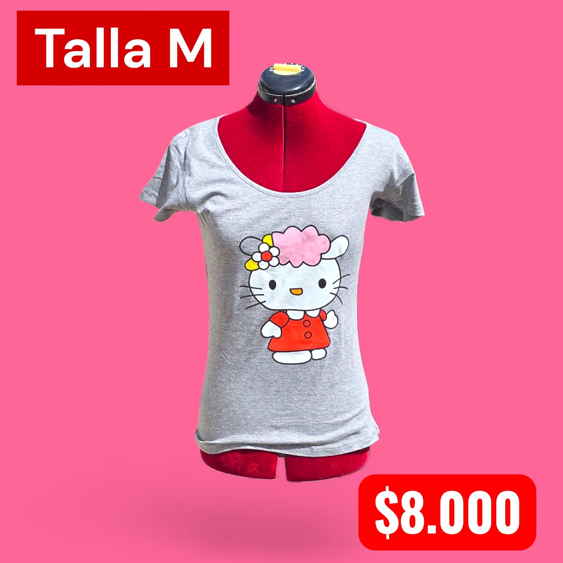 Mujer con camiseta gris de Hello Kitty, de pie al aire libre frente a vegetación.