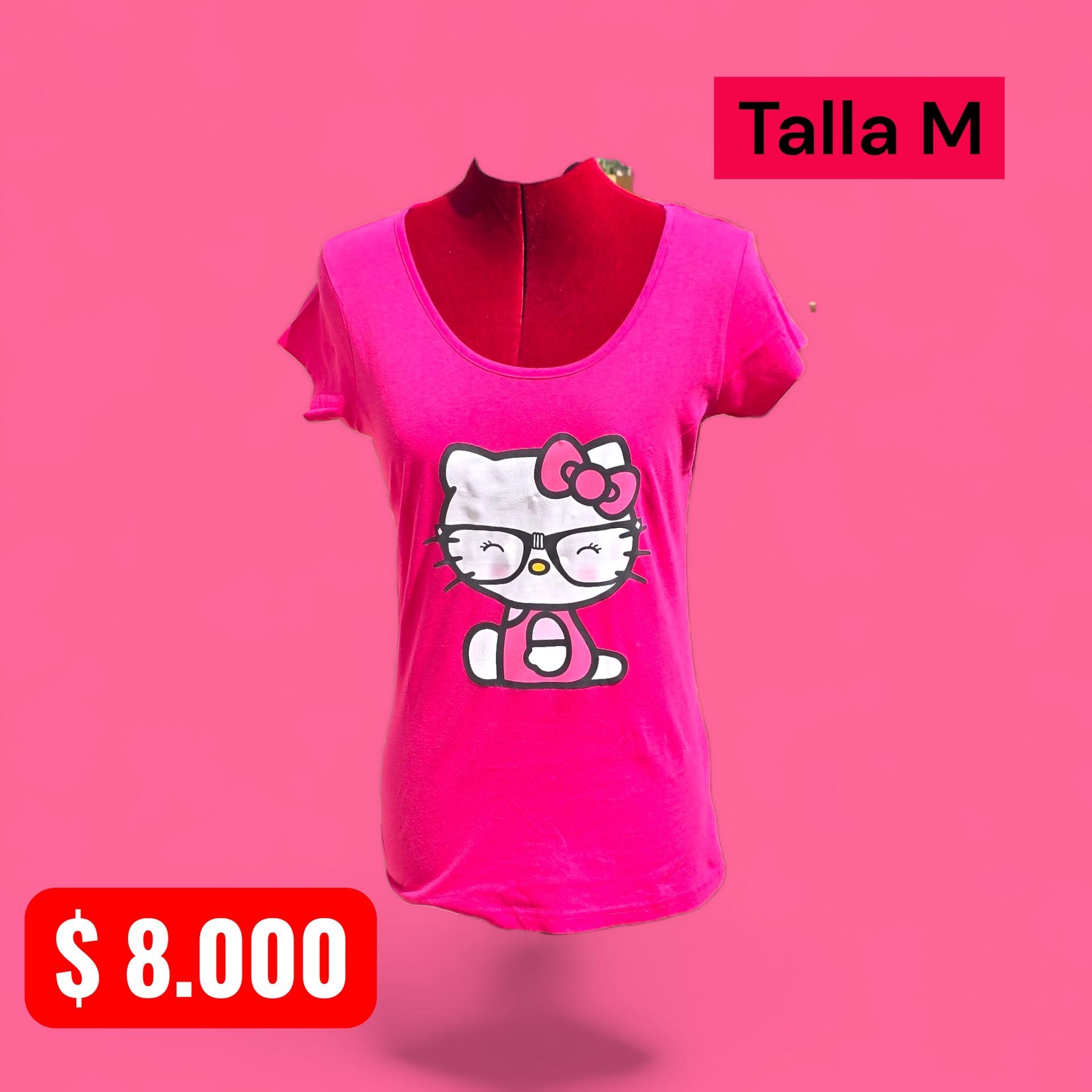 Mujer con camiseta rosa de Hello Kitty, vaqueros negros rotos y botas negras, apoyada en una pared de ladrillo con grafitis.