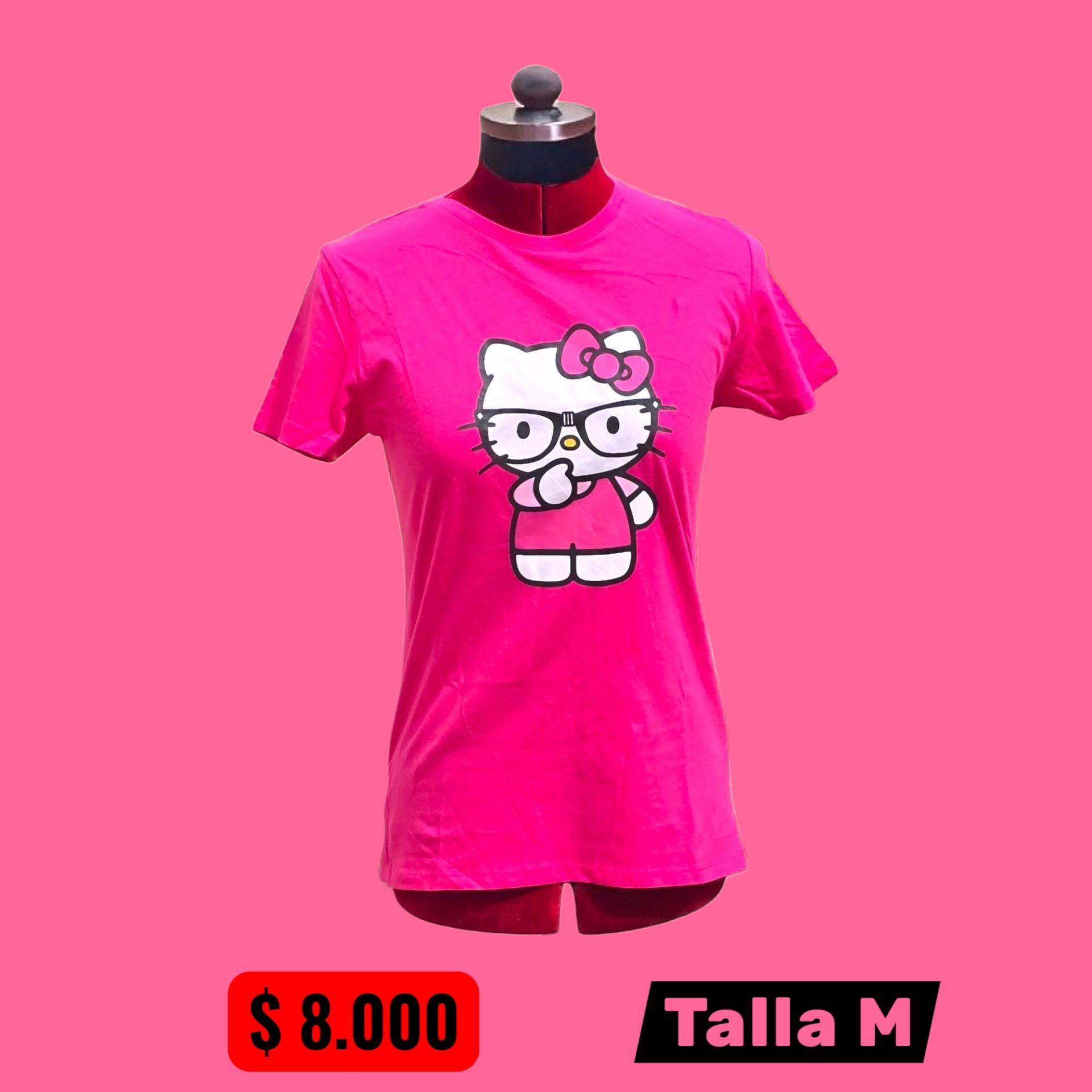 Persona con camiseta rosa de Hello Kitty y vaqueros negros rotos, de pie en una calle adoquinada.