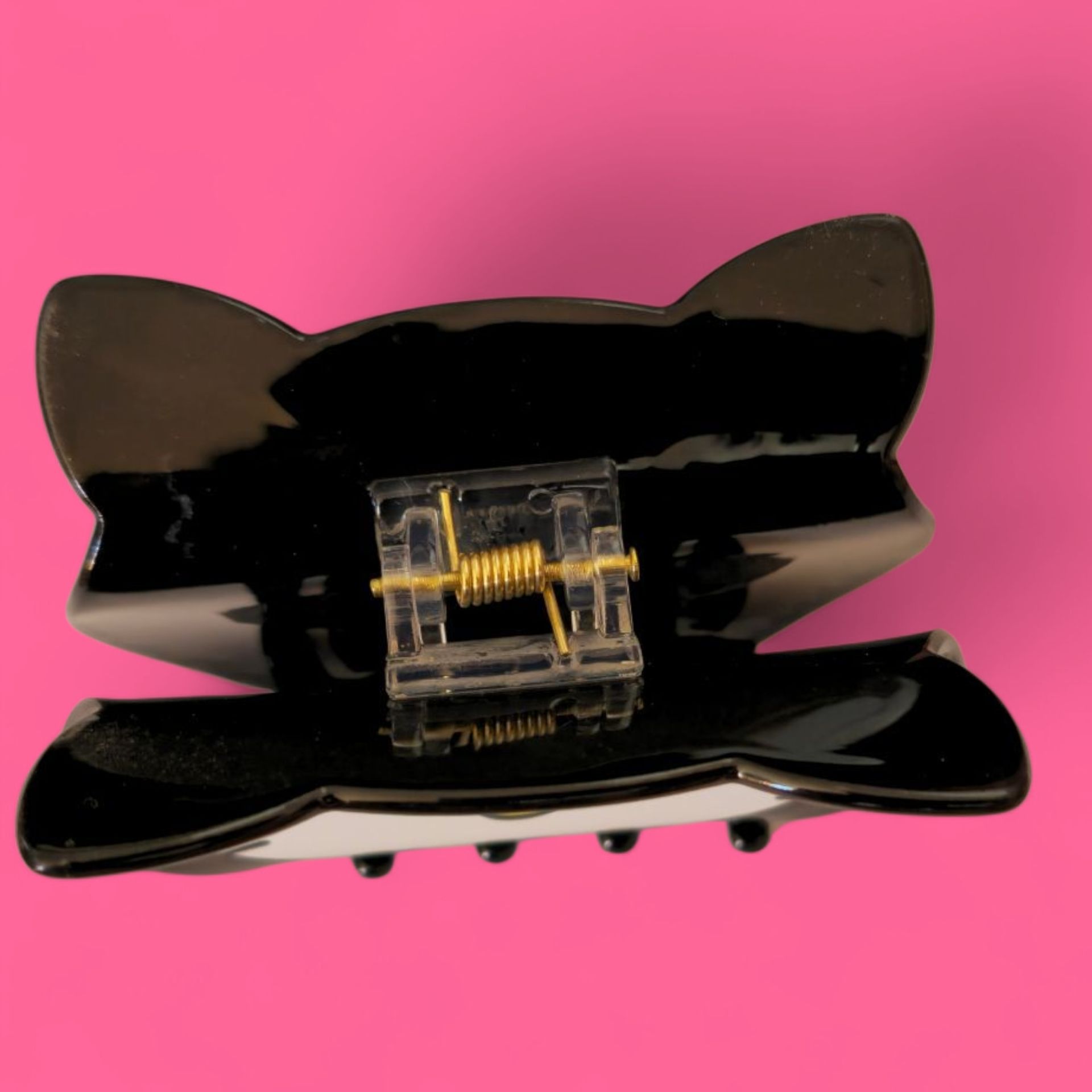 Pinza para el pelo Hello Kitty negra con orejas moradas, detalles naranjas y lazo rojo.