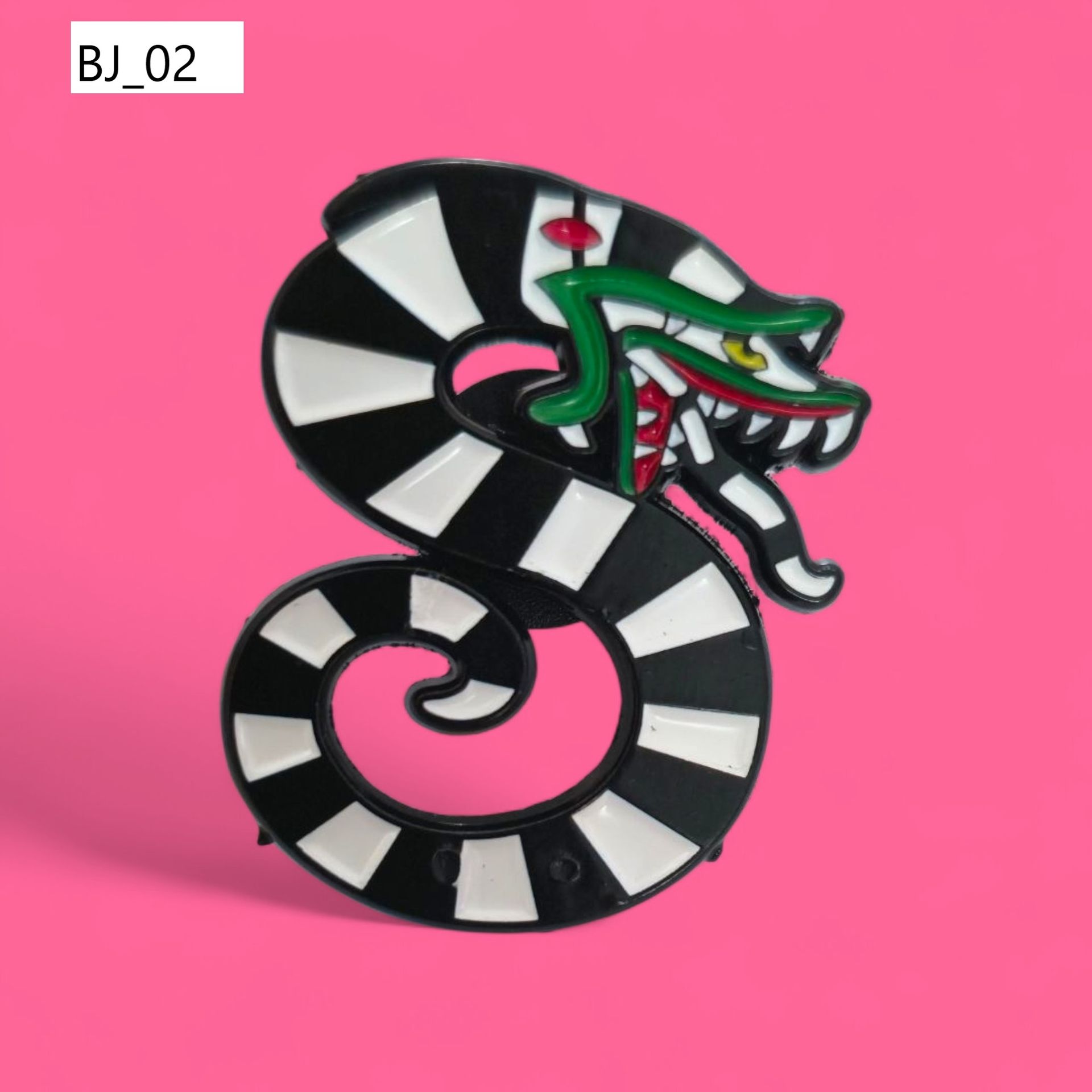Pin de esmalte de Beetlejuice sobre fondo rosa, con traje de rayas, cabello amarillo y dientes verdes.