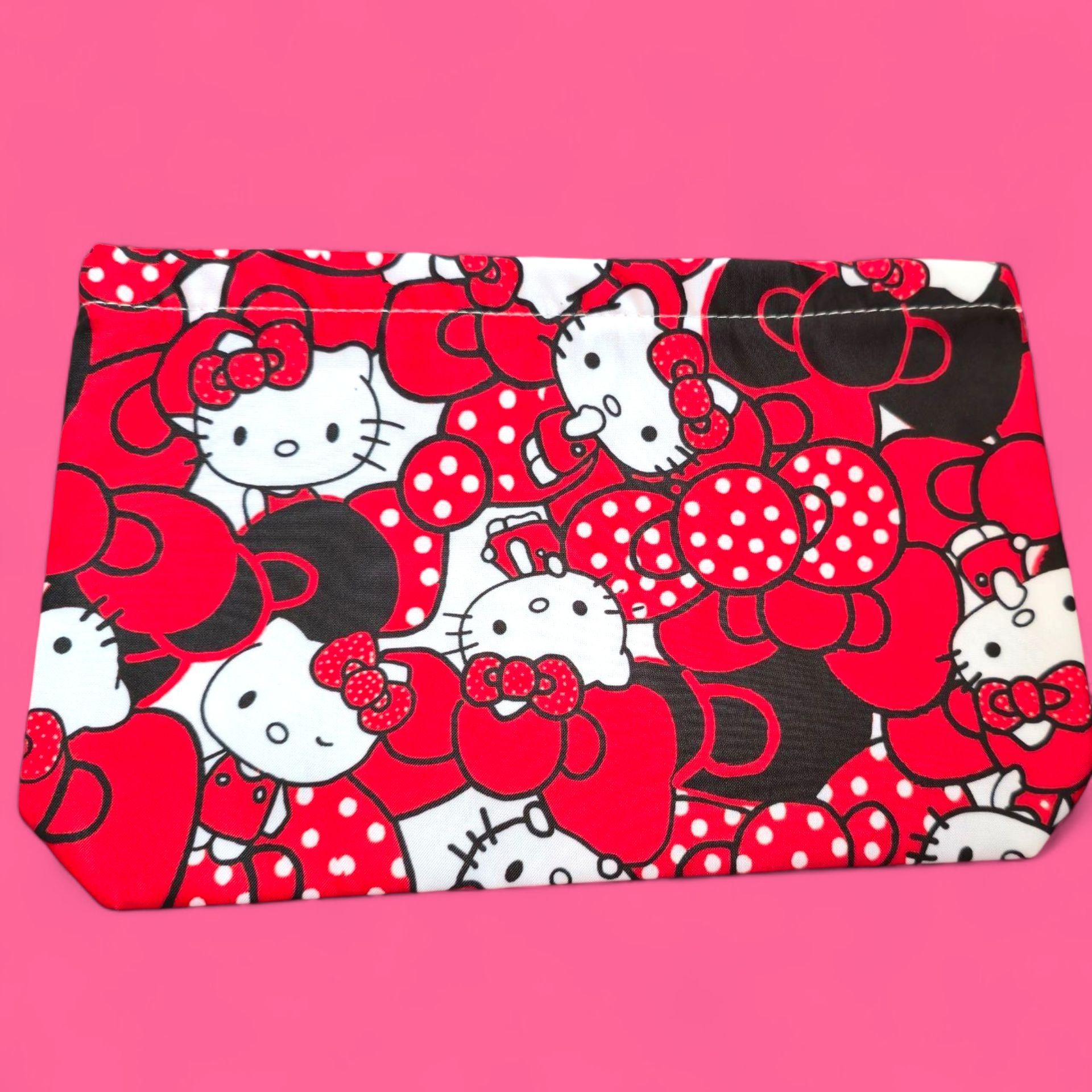 Bolsita con estampado de Hello Kitty, roja, blanca y negra, sobre fondo rosa.