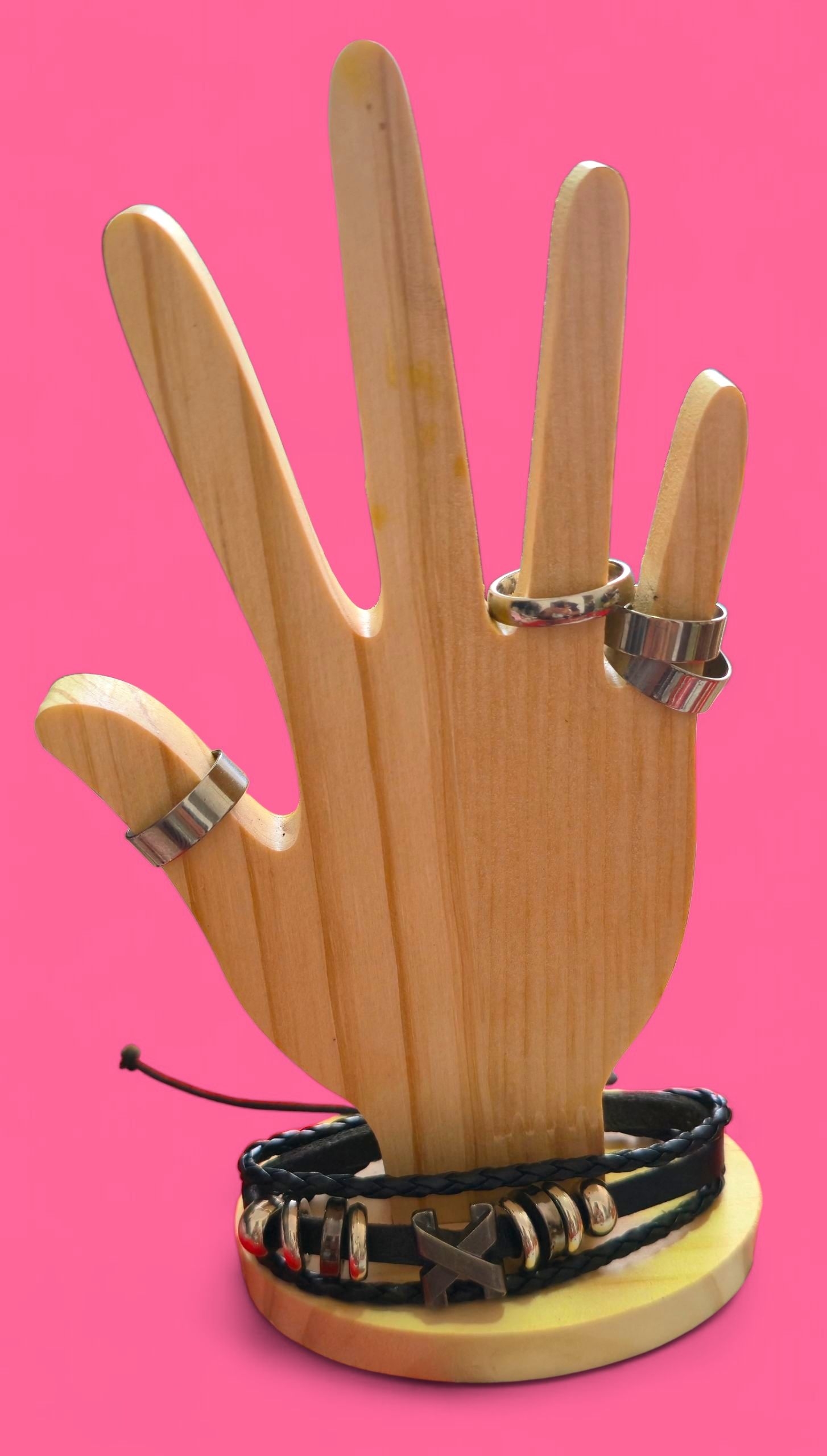 Pulsera de cuero negro con detalles de metal exhibida sobre un soporte de madera sobre un fondo rosa.