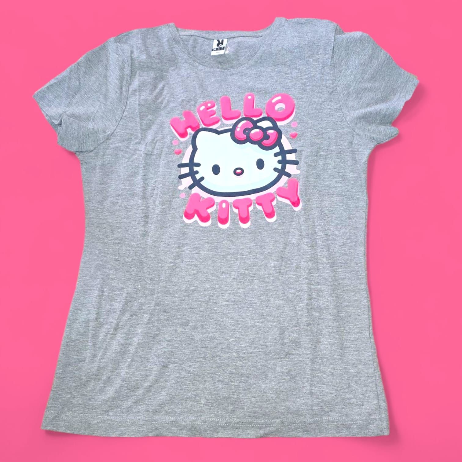 Mujer rapada en un callejón, vestida con una camiseta de Hello Kitty, vaqueros rotos y botas, con joyas oscuras.