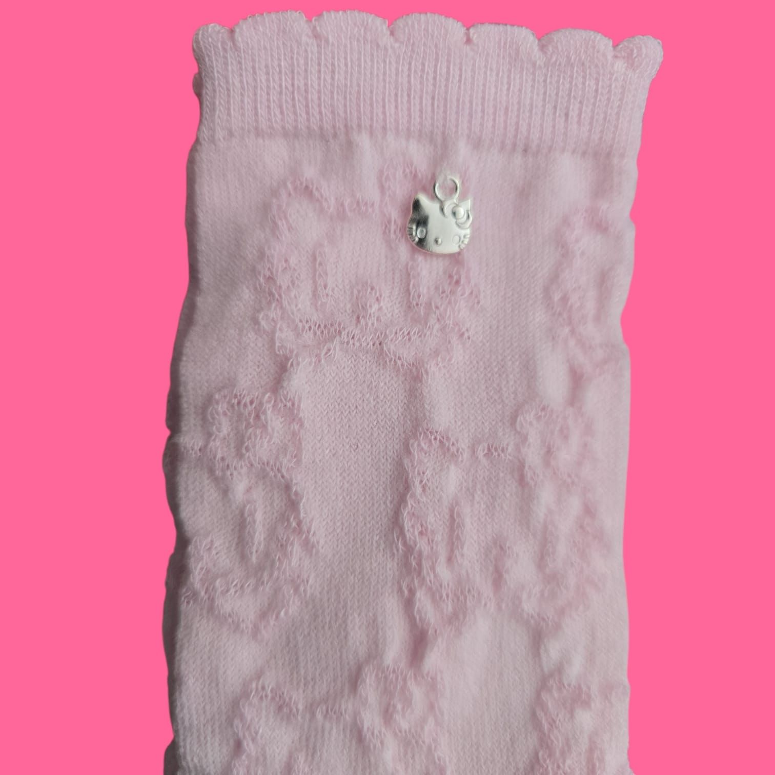 Dos calcetines de encaje rosa claro sobre fondo rosa, con pequeños adornos decorativos.