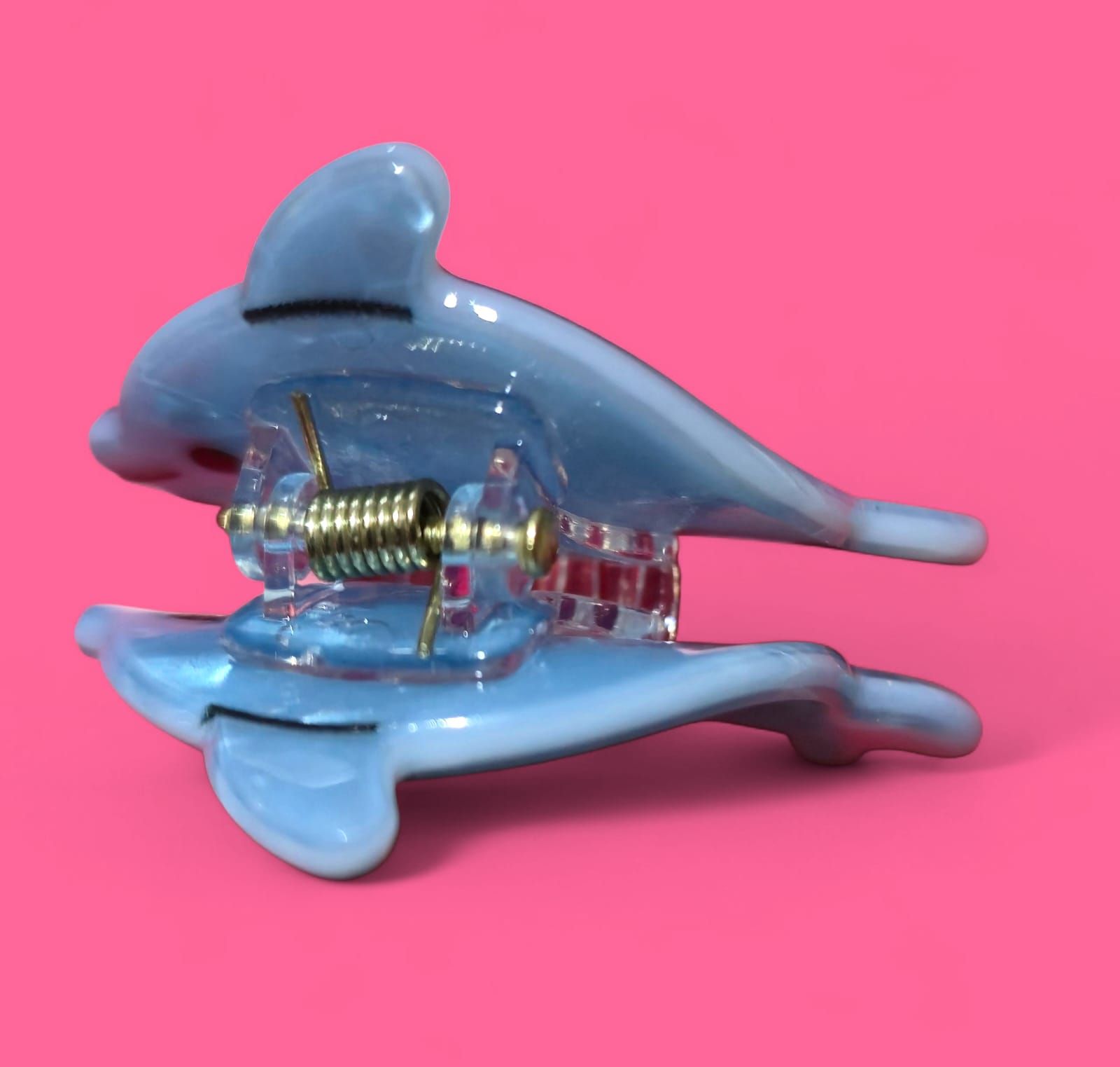 Dos figuras de delfines de color azul claro, una delante de la otra, sobre un fondo rosa.