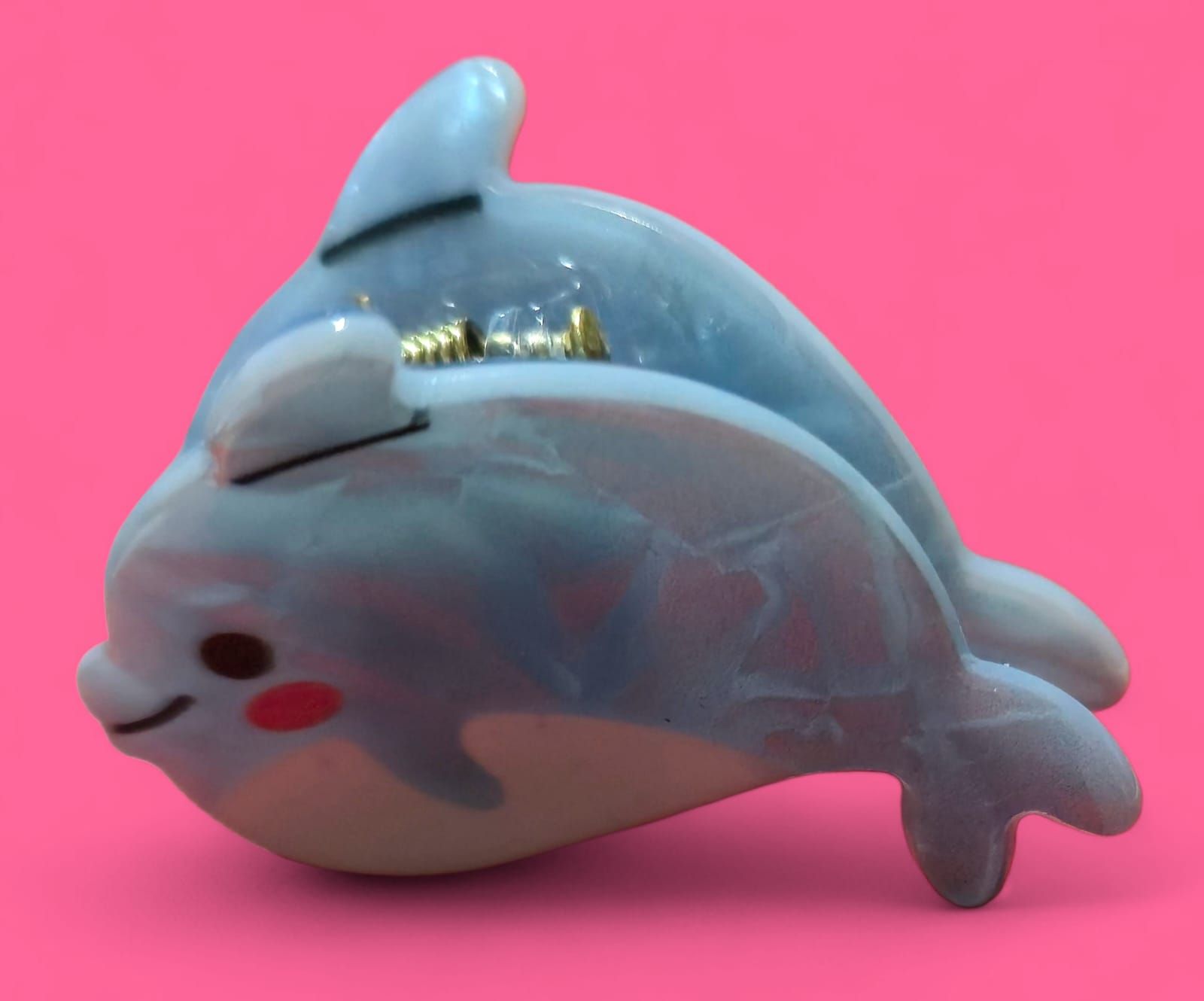 Dos figuras de delfines de color azul claro, una delante de la otra, sobre un fondo rosa.