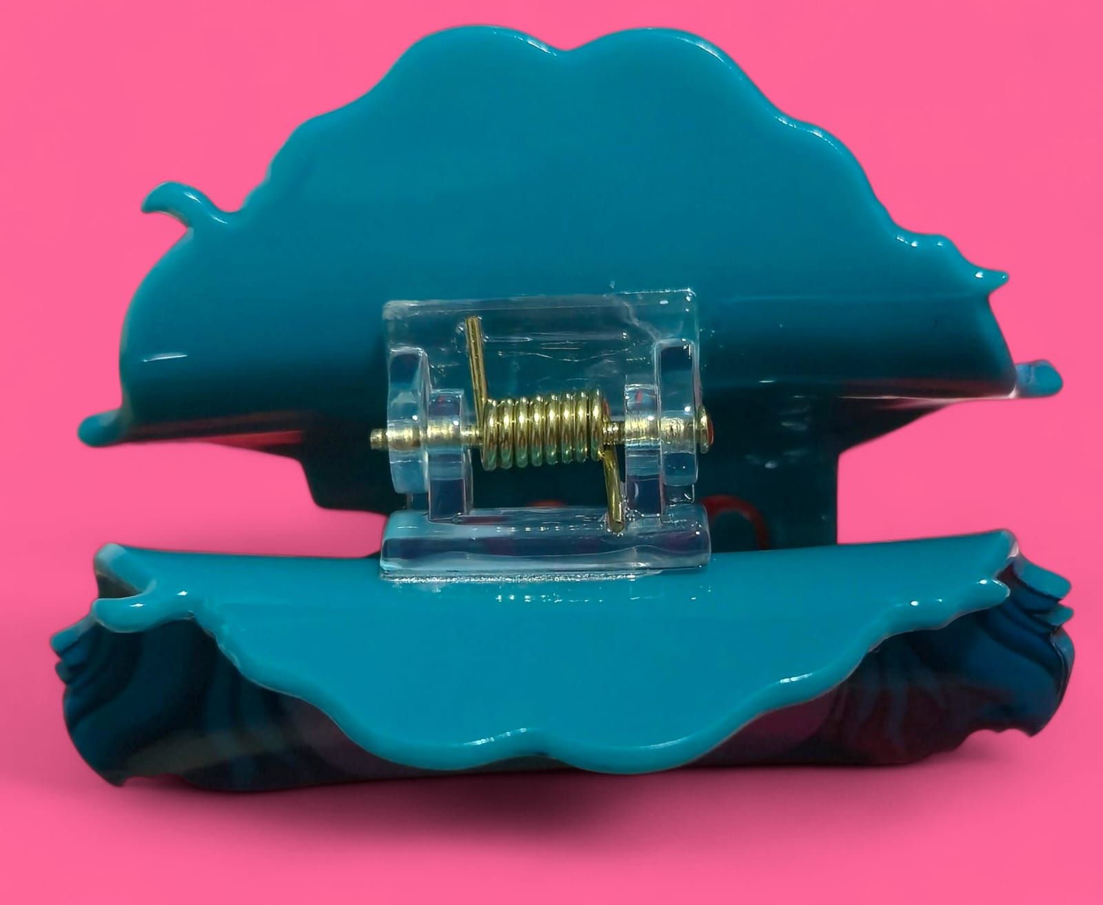 Juguete azul, de forma redonda, con ojos grandes y pelo, sobre un fondo rosa.