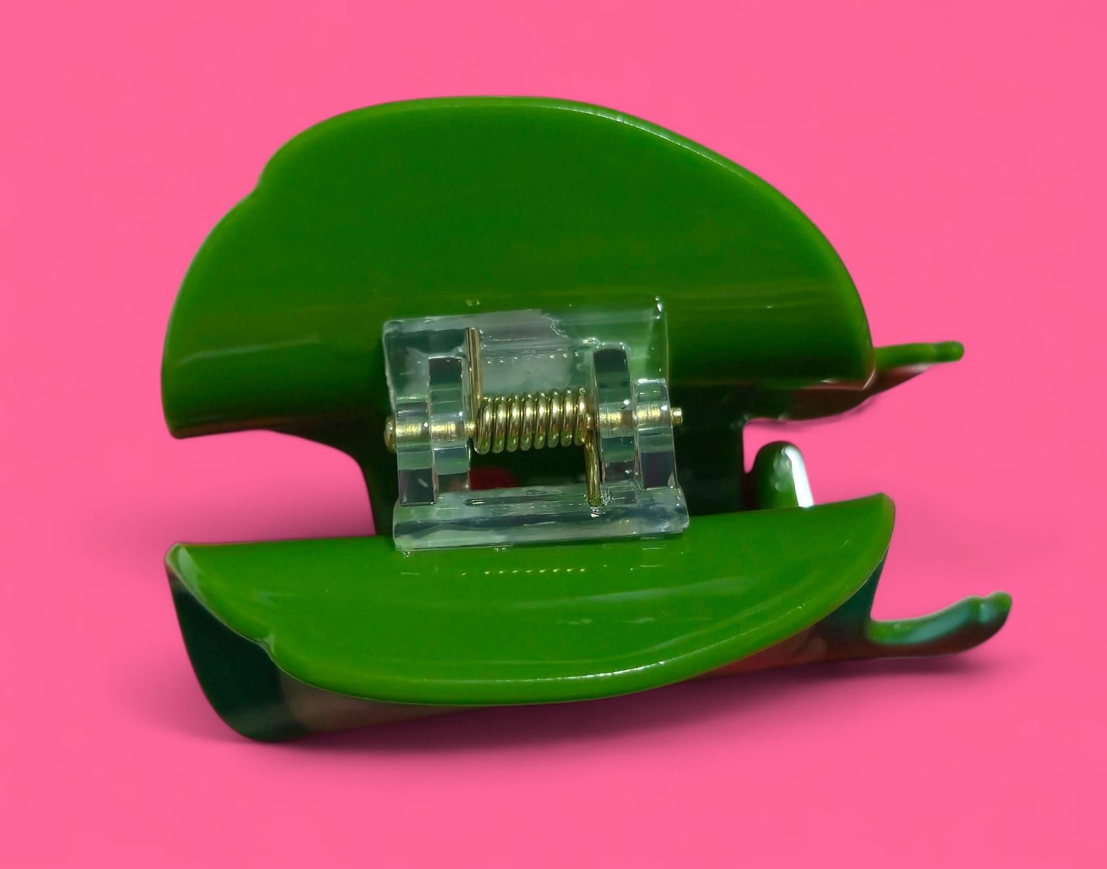 Primer plano de Asco de la película Inside Out, en color verde, con expresión de asco, sobre un fondo rosa.