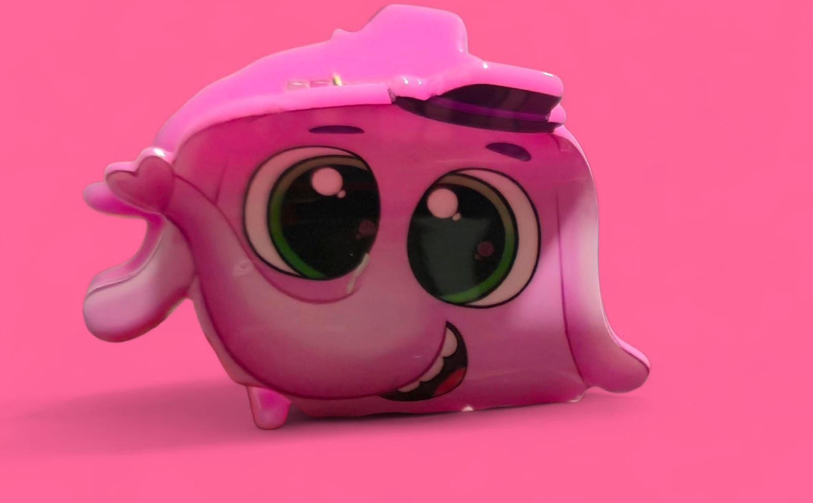 Personaje de dibujos animados rosa con grandes ojos verdes y expresión sonriente.
