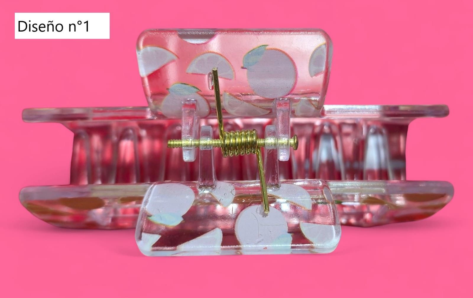 Pinza para el cabello con diseño de fruta naranja sobre fondo rosa.