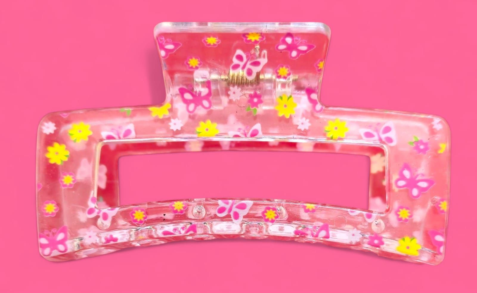 Pinza para el cabello con estampado de mariposas y flores rosas sobre fondo rosa.