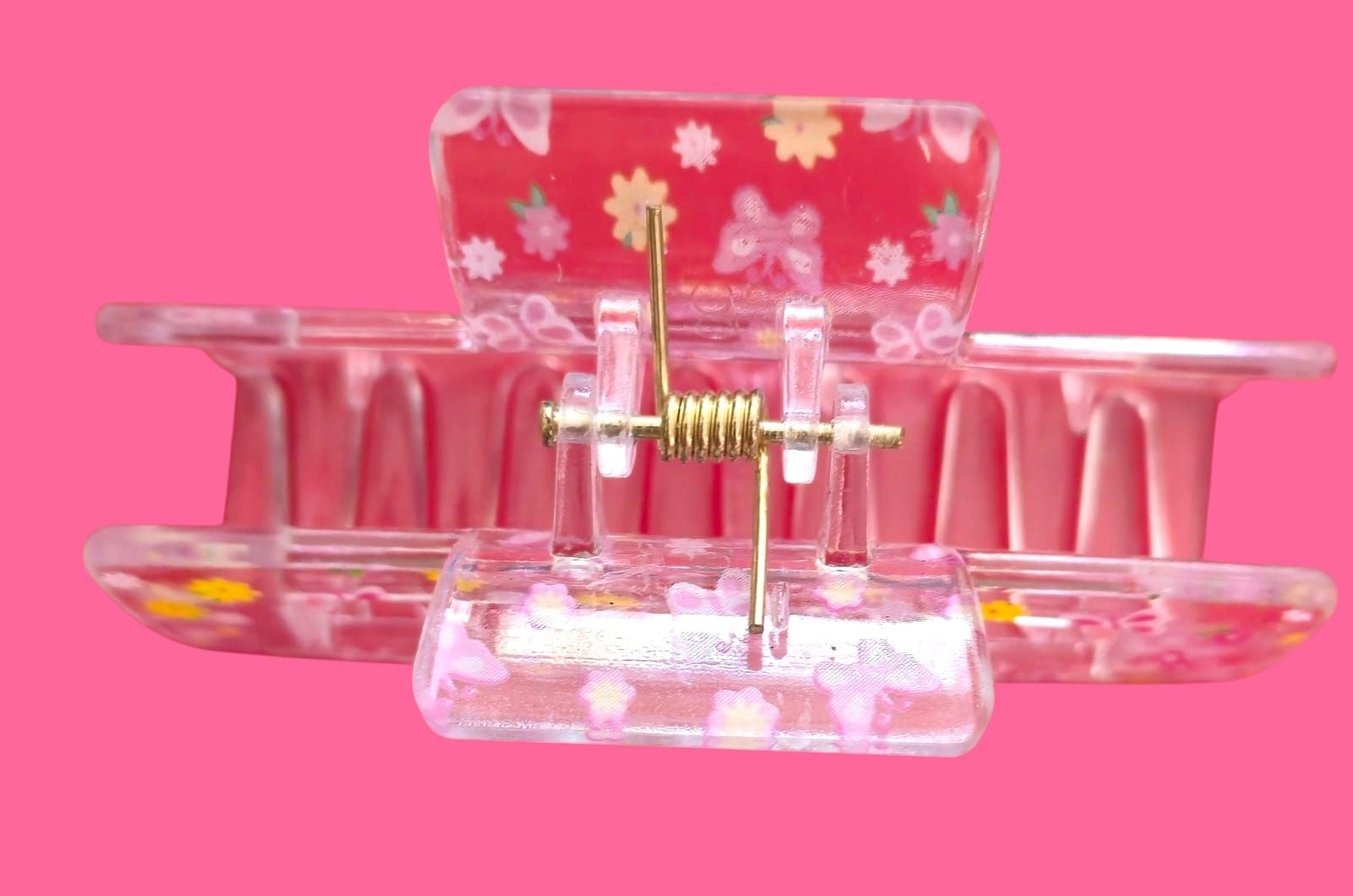 Pinza para el cabello con estampado de mariposas y flores rosas sobre fondo rosa.