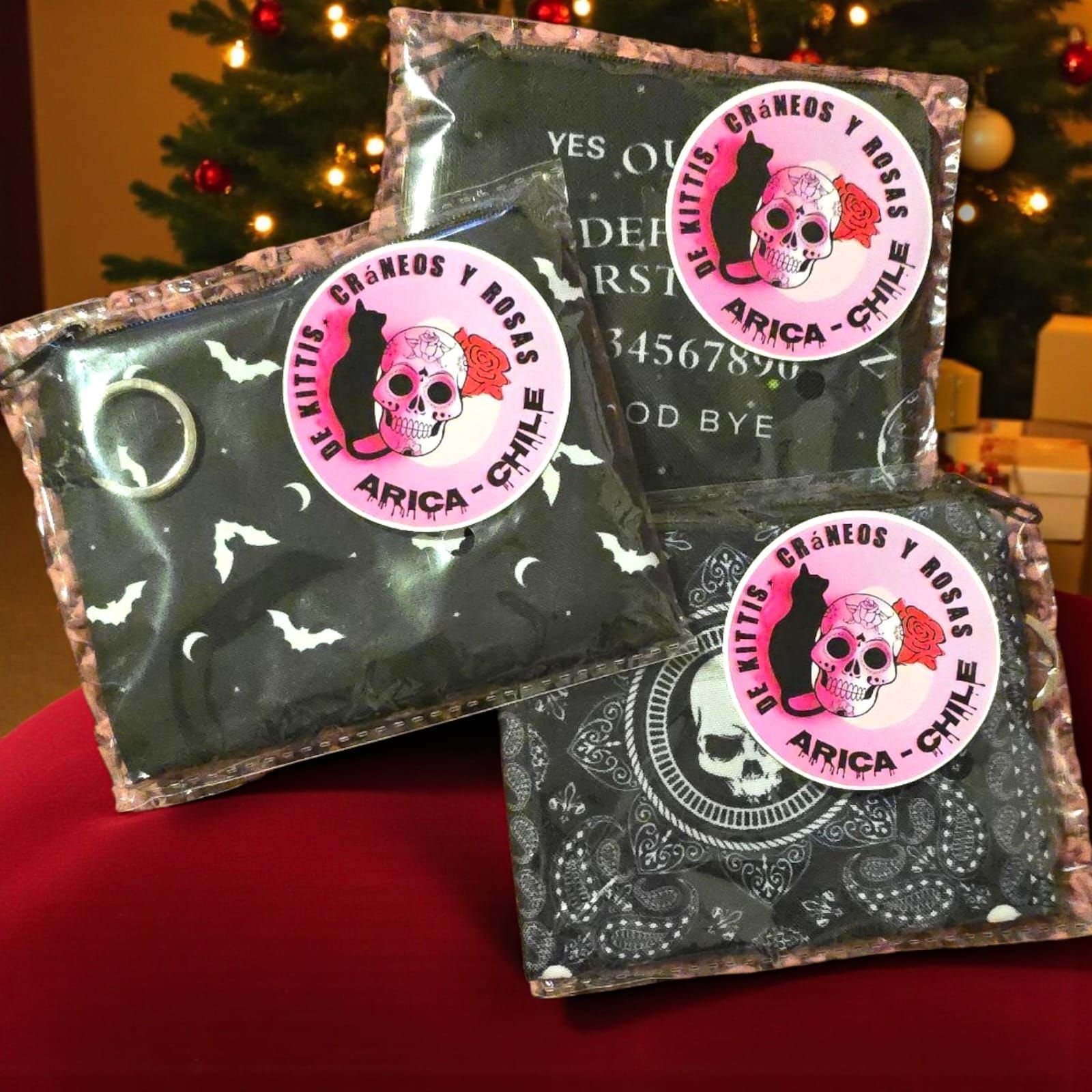 Tres bolsas negras empaquetadas con pegatinas de calaveras, junto a un árbol de Navidad.