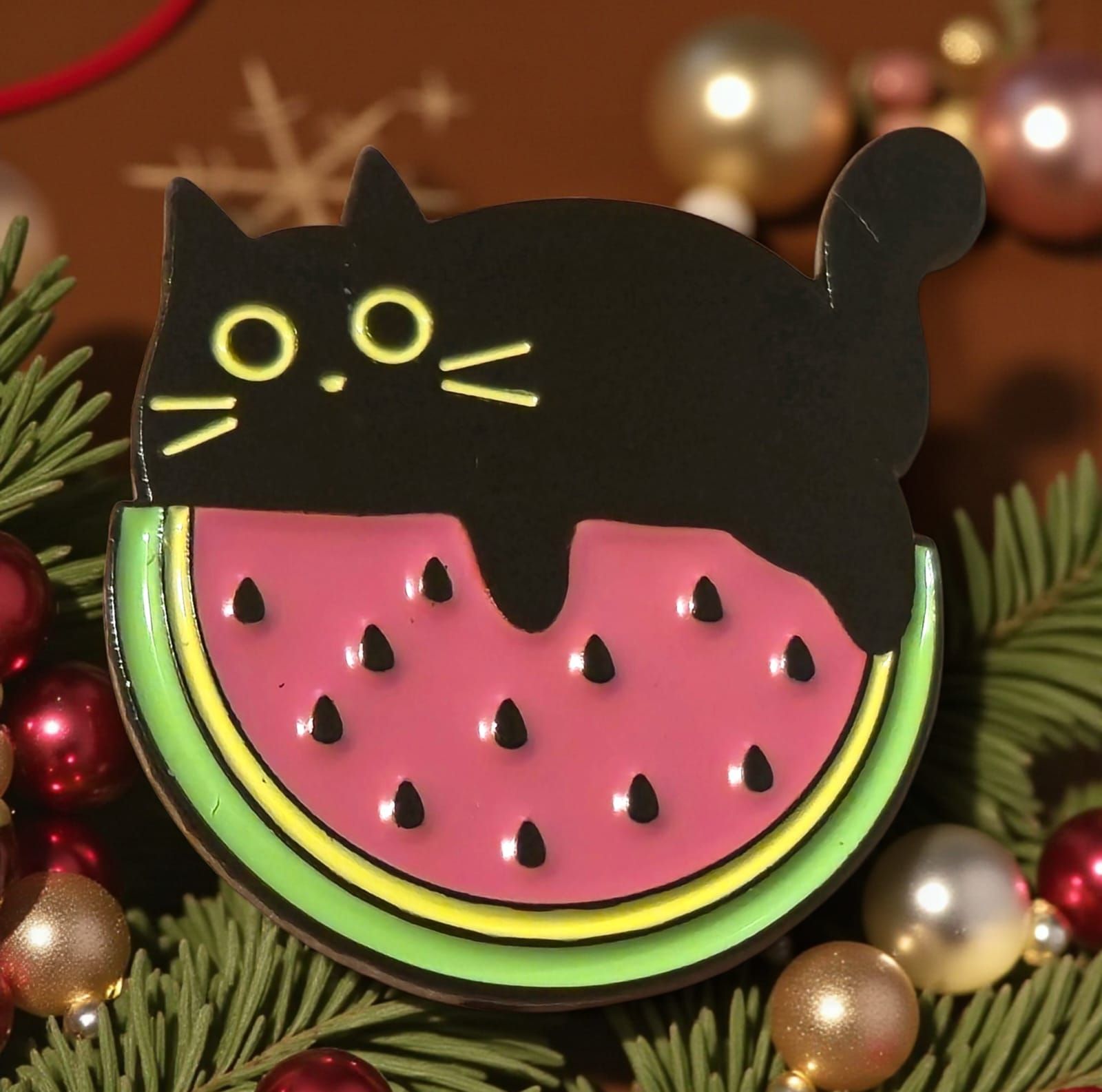 Pin esmaltado de un gato negro sobre una rodaja de sandía. Verde, rosa y negro.