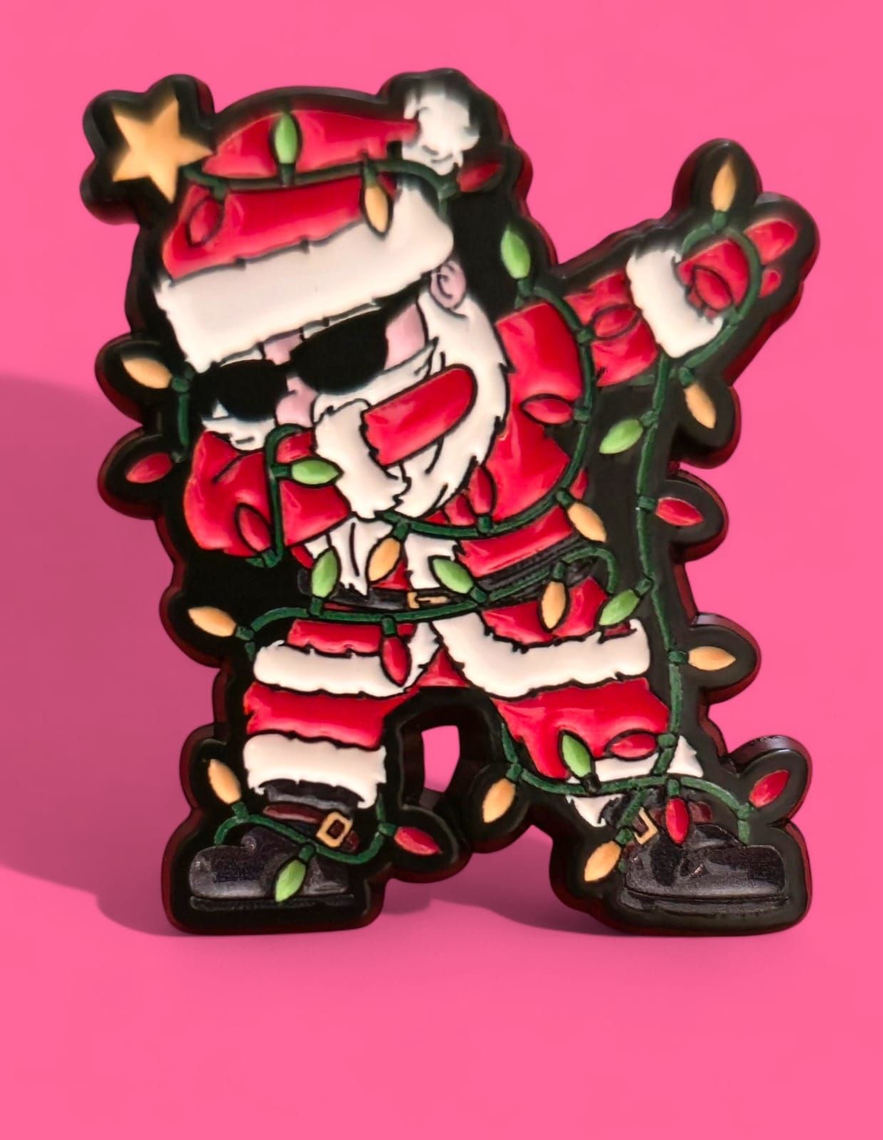 Papá Noel haciendo el dab, con gafas de sol y luces navideñas, sobre un fondo rosa.