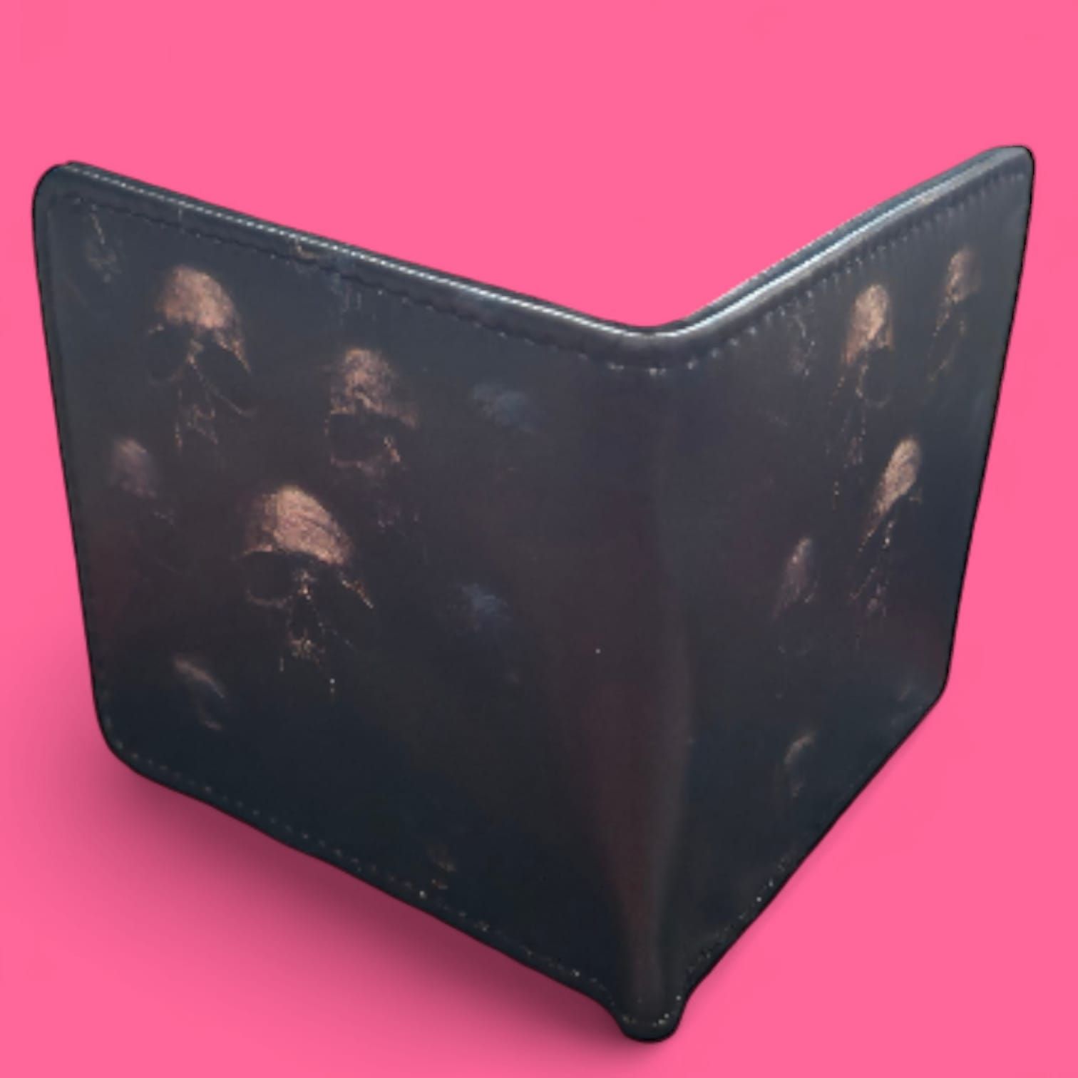 Cartera negra con un estampado de calavera oscura sobre fondo rosa.