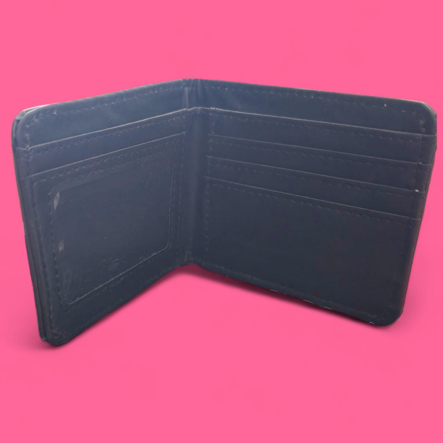 Cartera negra con un estampado de calavera oscura sobre fondo rosa.