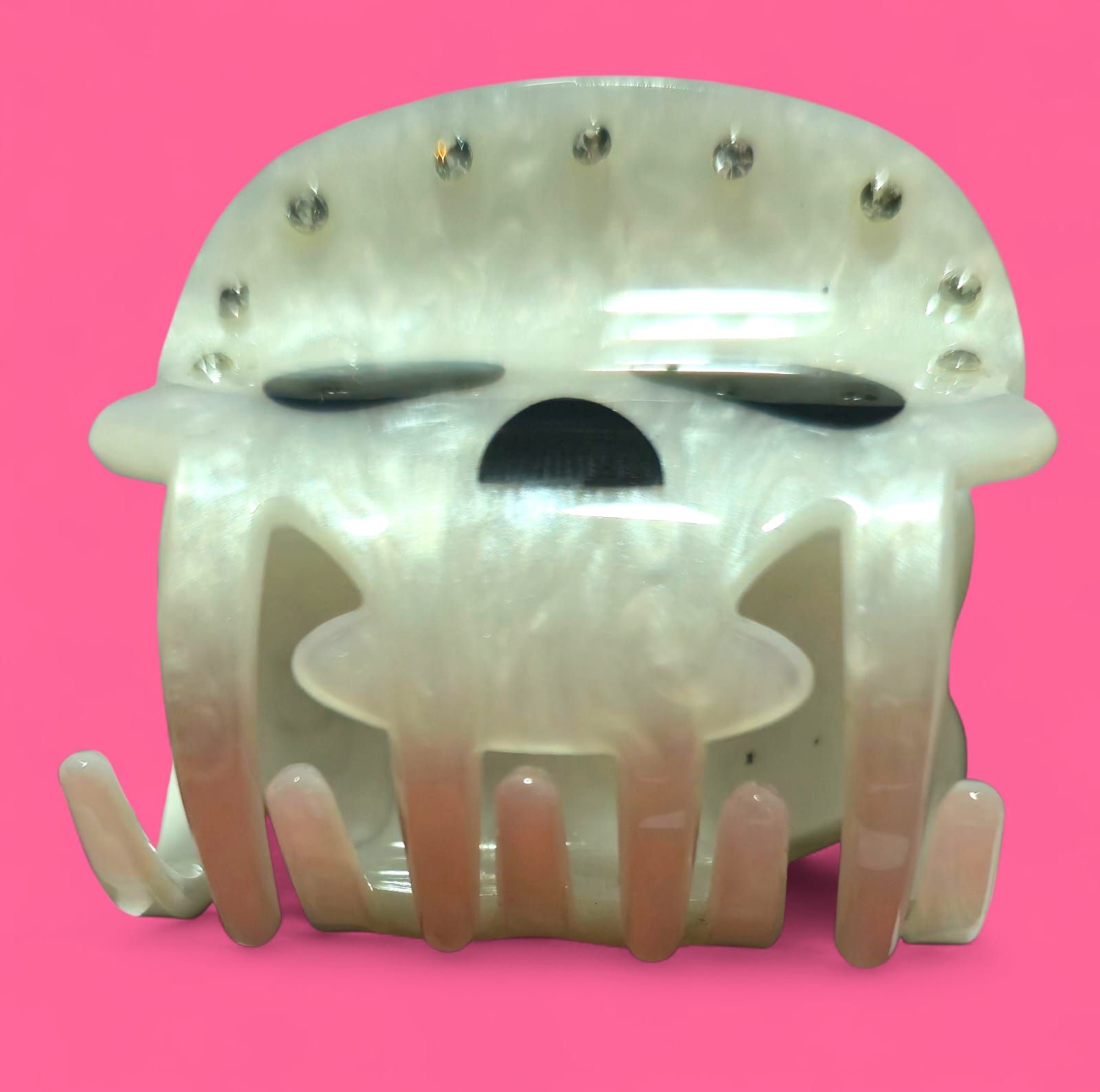 Pinza para el pelo blanca con forma de calavera, con cuencas negras para los ojos y la nariz, pedrería y bisagra dorada.