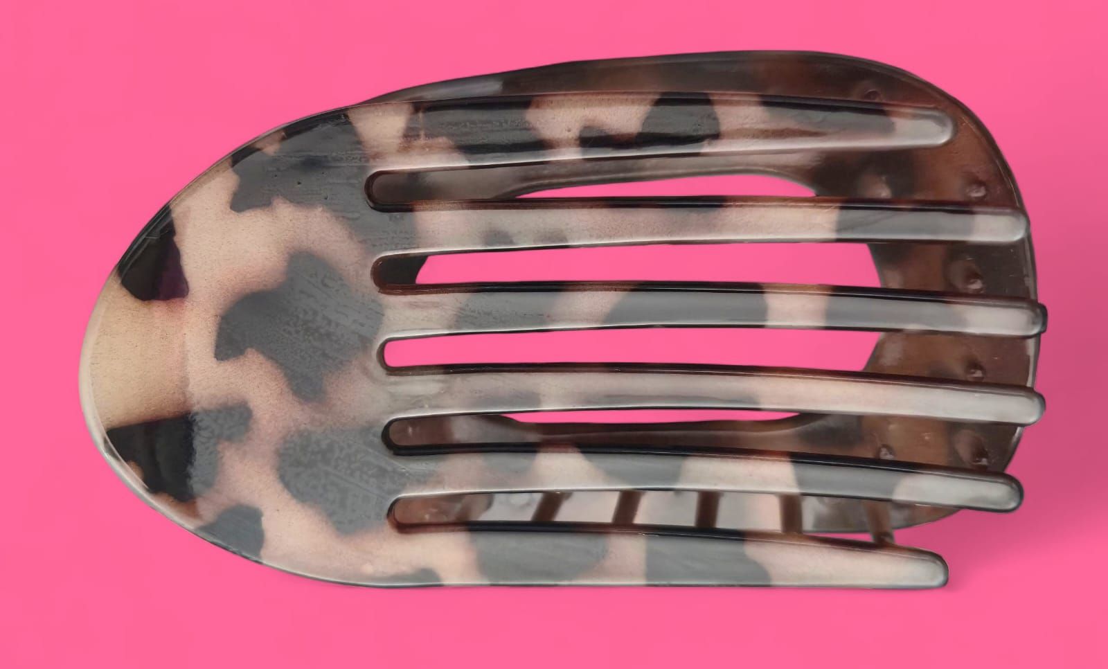 Pinza para el pelo con estampado de leopardo y rayas rosas sobre fondo rosa.