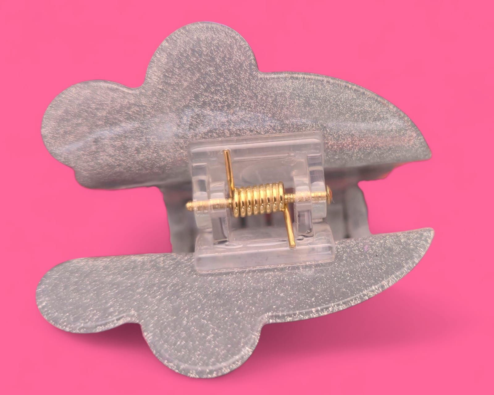 Calavera brillante con ojos en forma de corazón y un lazo rosa, sobre un fondo rosa.